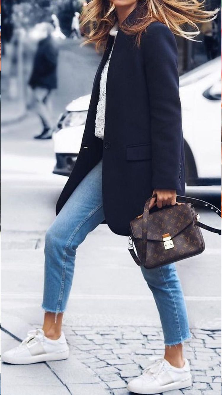 woman wearing sneakers and navy coat with light denim 