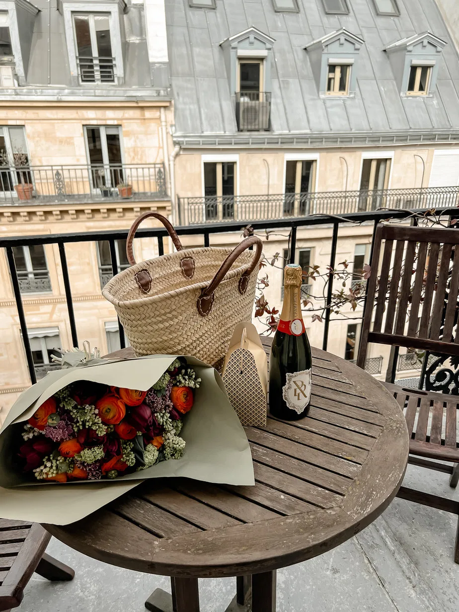 Flowers, wine, basket bag sitting on a table in Paris