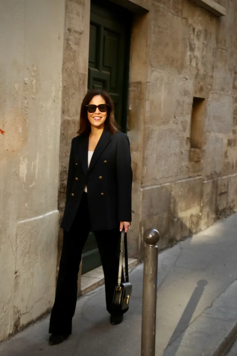 Woman wearing black blazer walking down the street.