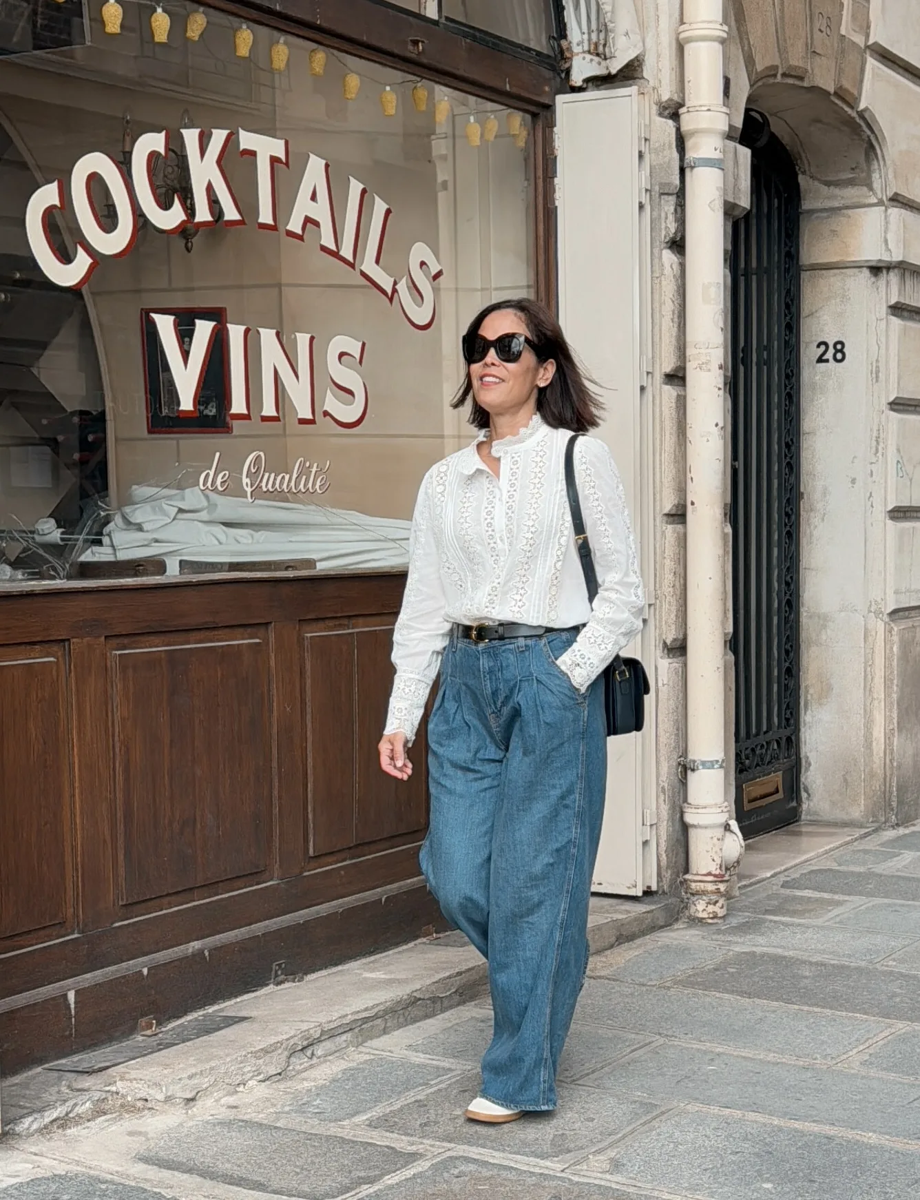 Woman walking with jeans and white button down blouse in Paris.