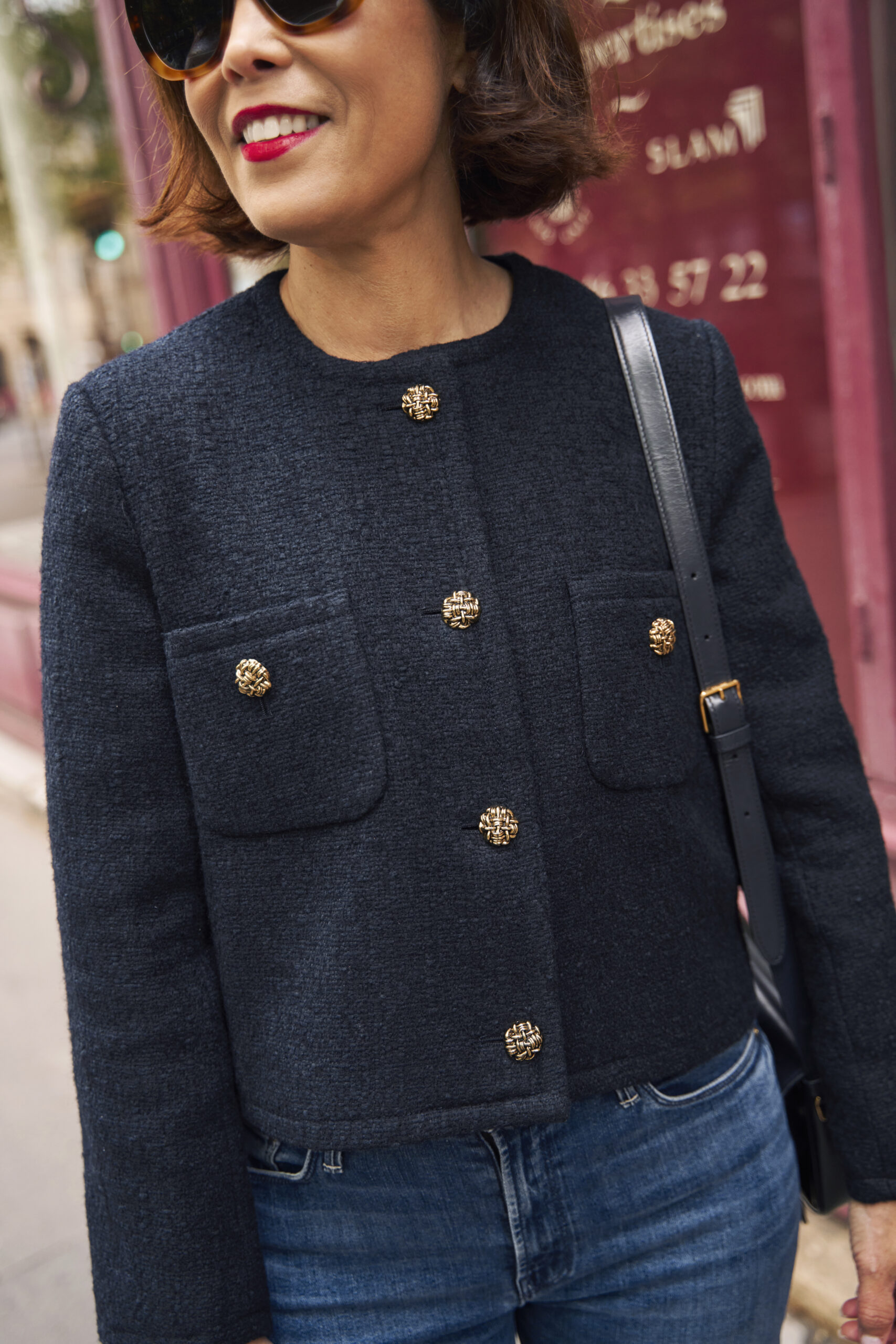 Woman wearing navy tweed jacket with denim and handbag in paris.