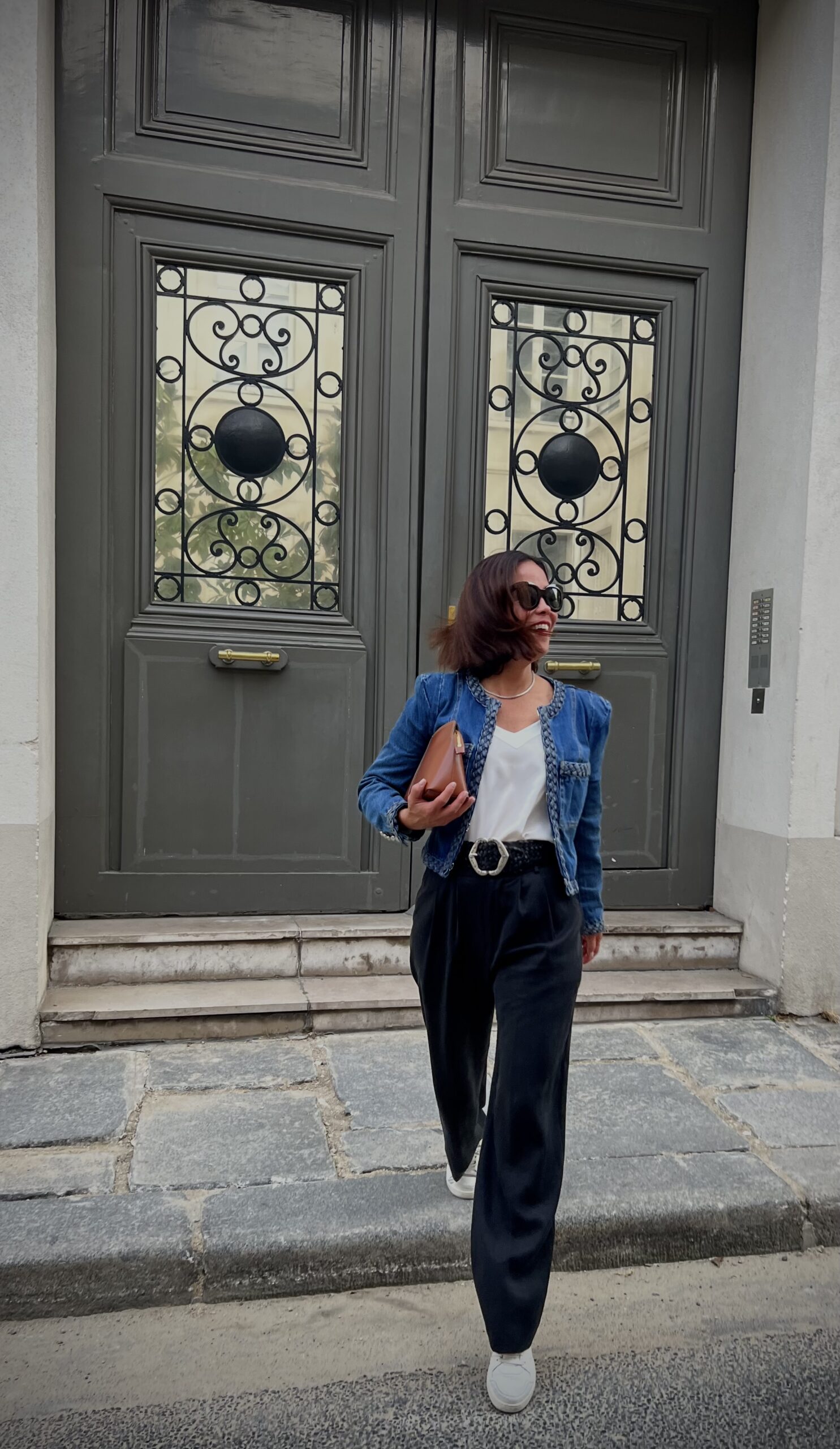Woman walking with denim jacket and silk cami layering pieces.