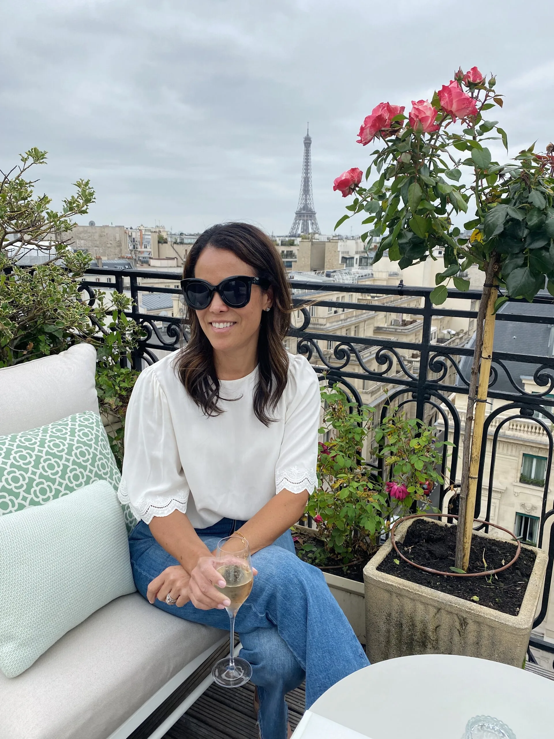 Woman sitting on a rooftop in Paris with a glass of wine.
