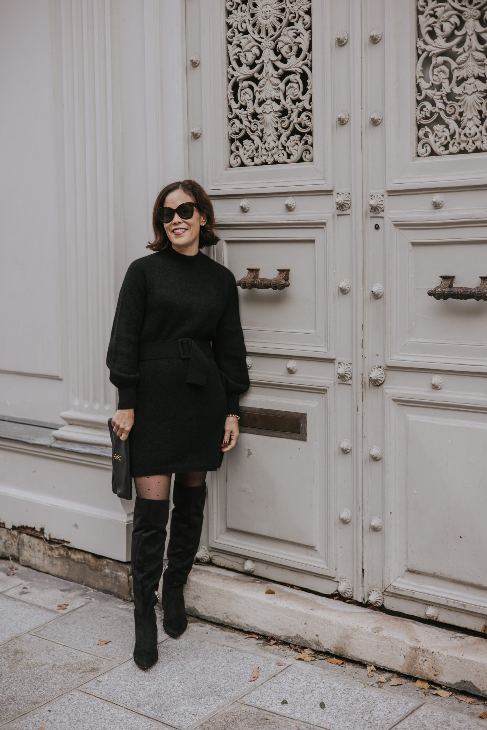Woman wearing black dress with tall boots.