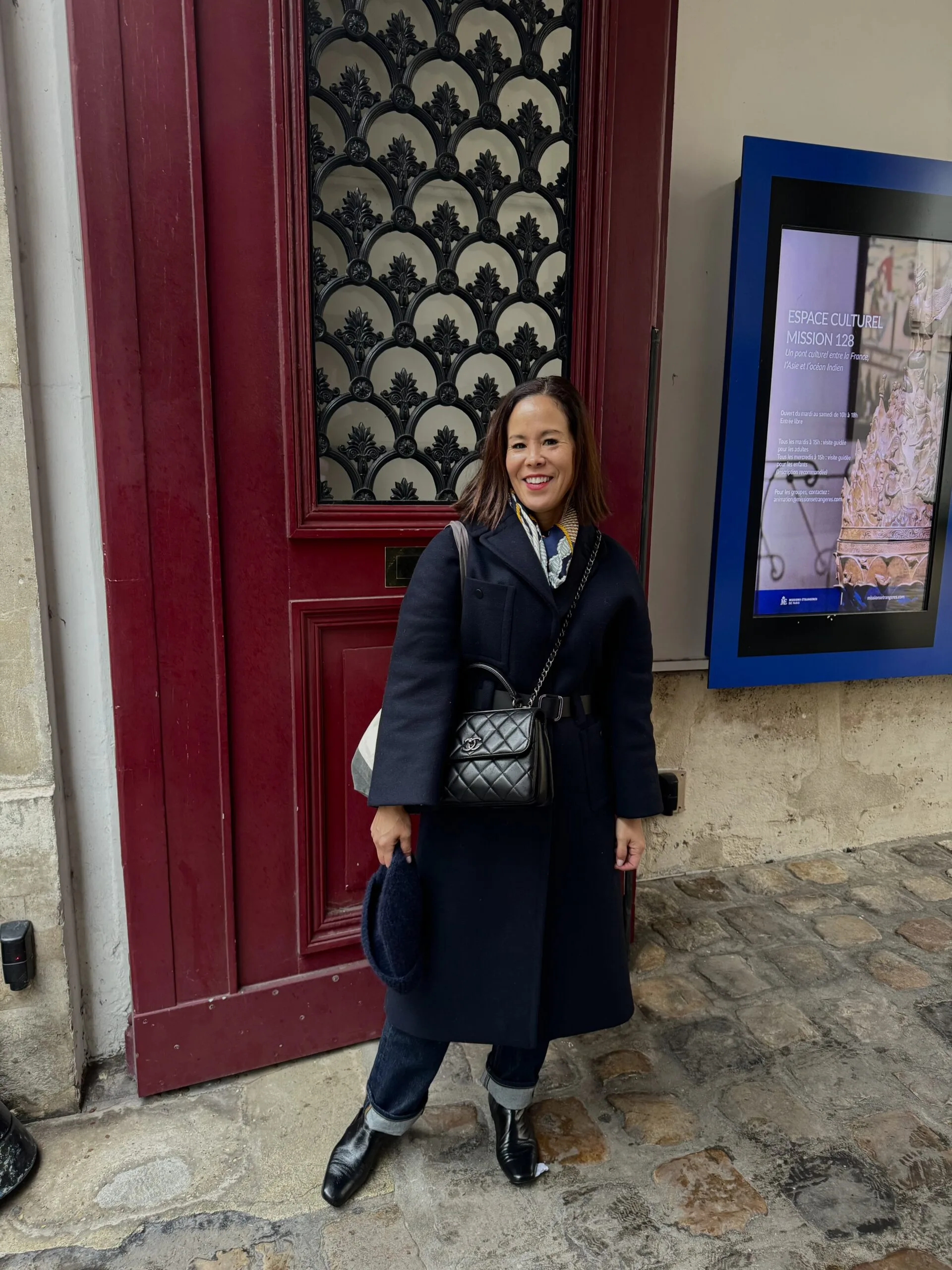 Woman wearing wool coat in winter in front of red door.