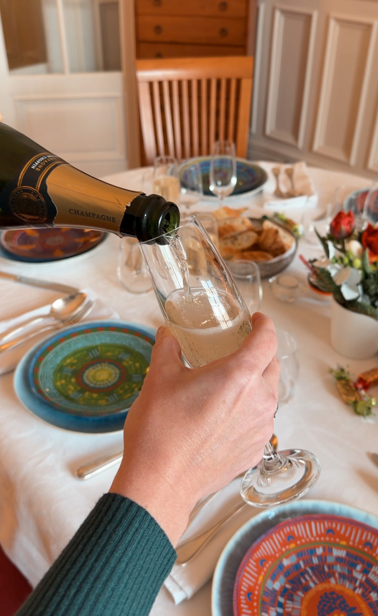 Woman pouring champagne into a glass over a table.