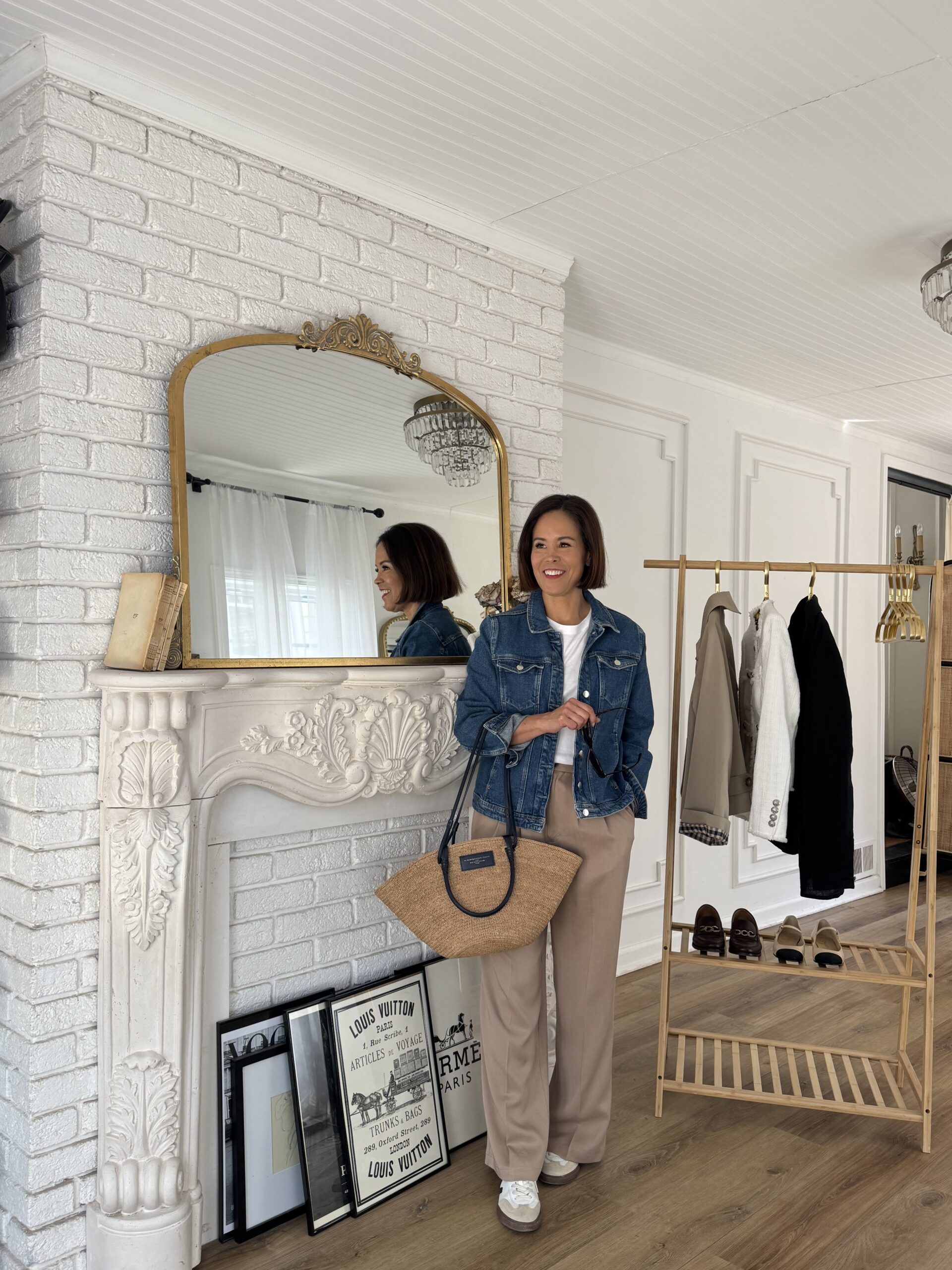 Chic French-inspired spring outfit featuring a classic denim jacket styled with neutral trousers, white sneakers, and a straw tote for an effortless Parisian look