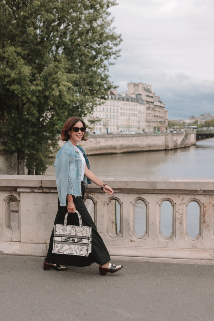 Noelani wearing loafers with wide-leg trousers and denim jacket walking along the Seine River in Paris, French girl spring style.