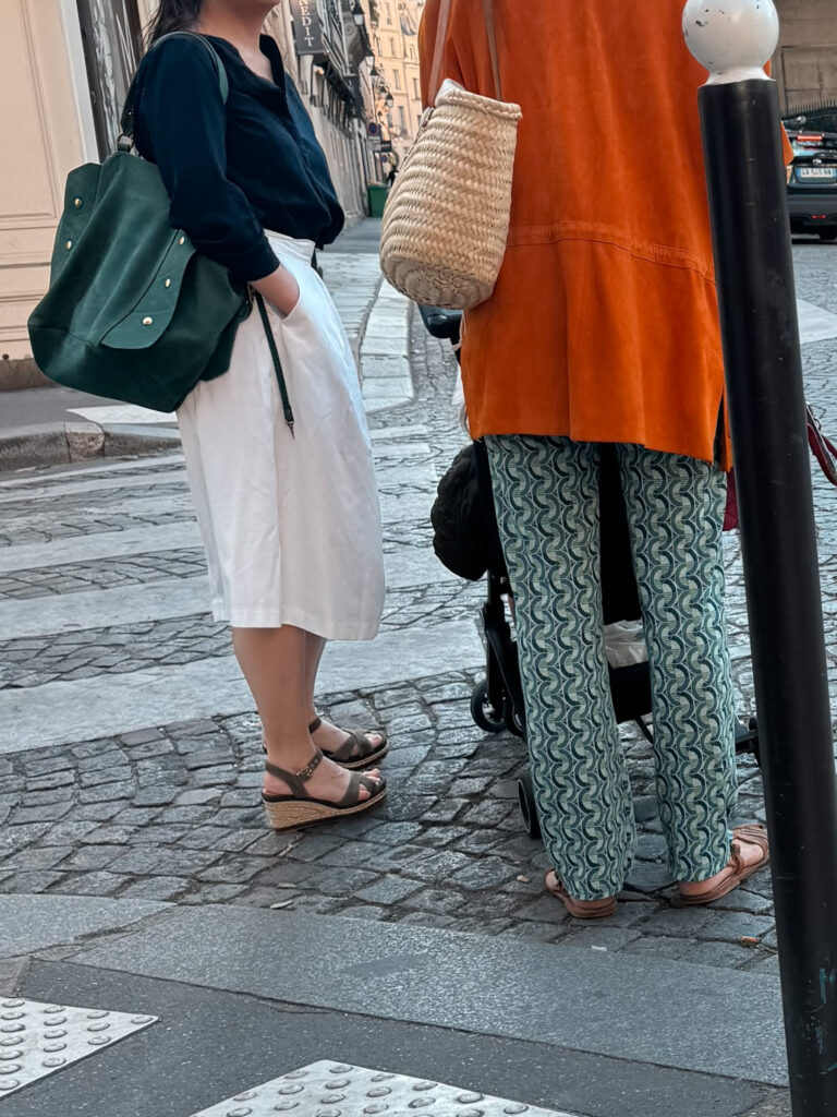 Parisian women wearing wedge espadrilles and sandals with white midi skirt and basket bag on Paris street, French spring shoe style.