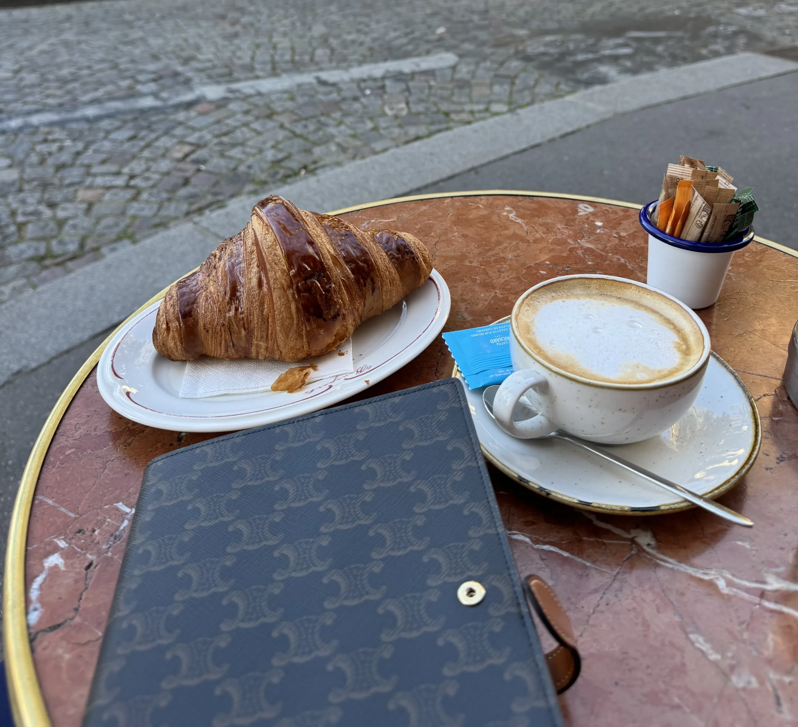 notebook and croissant sitting on a table in Paris.