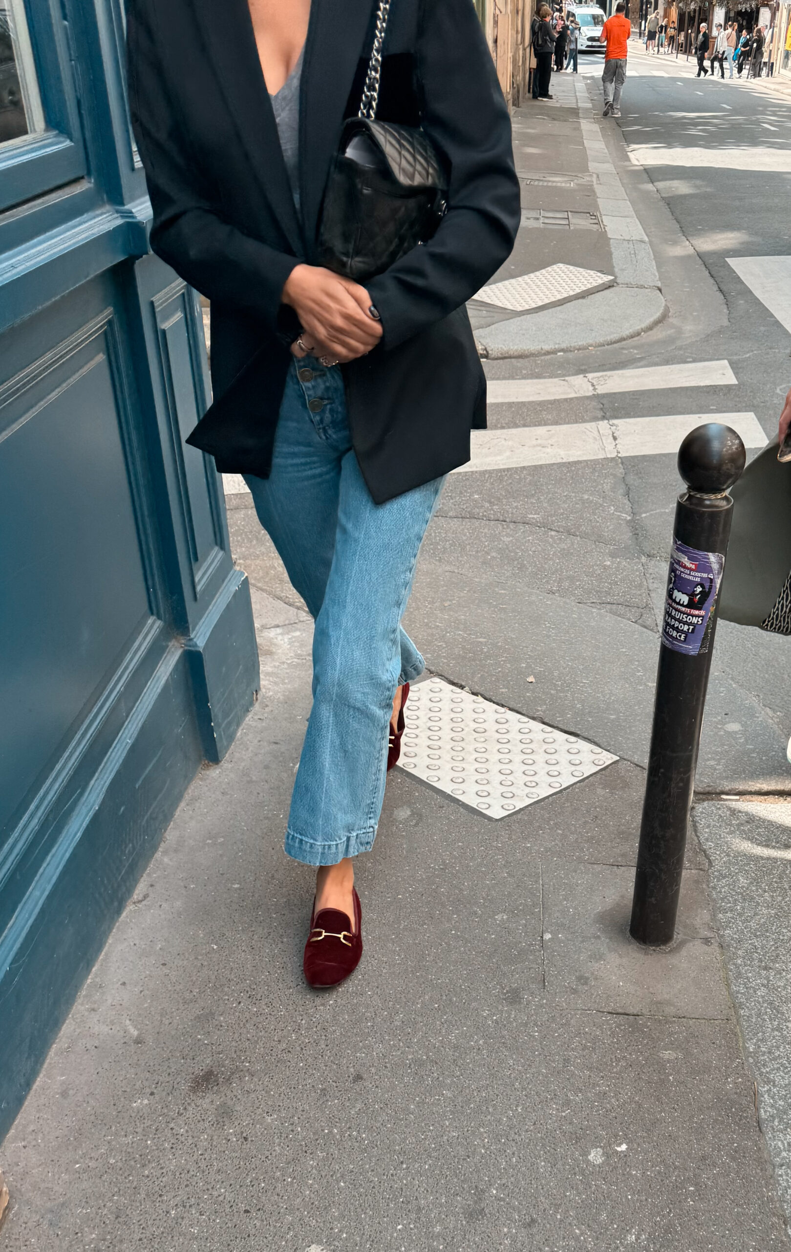 Burgundy velvet horsebit loafers with cropped jeans and a black blazer on a Paris street.