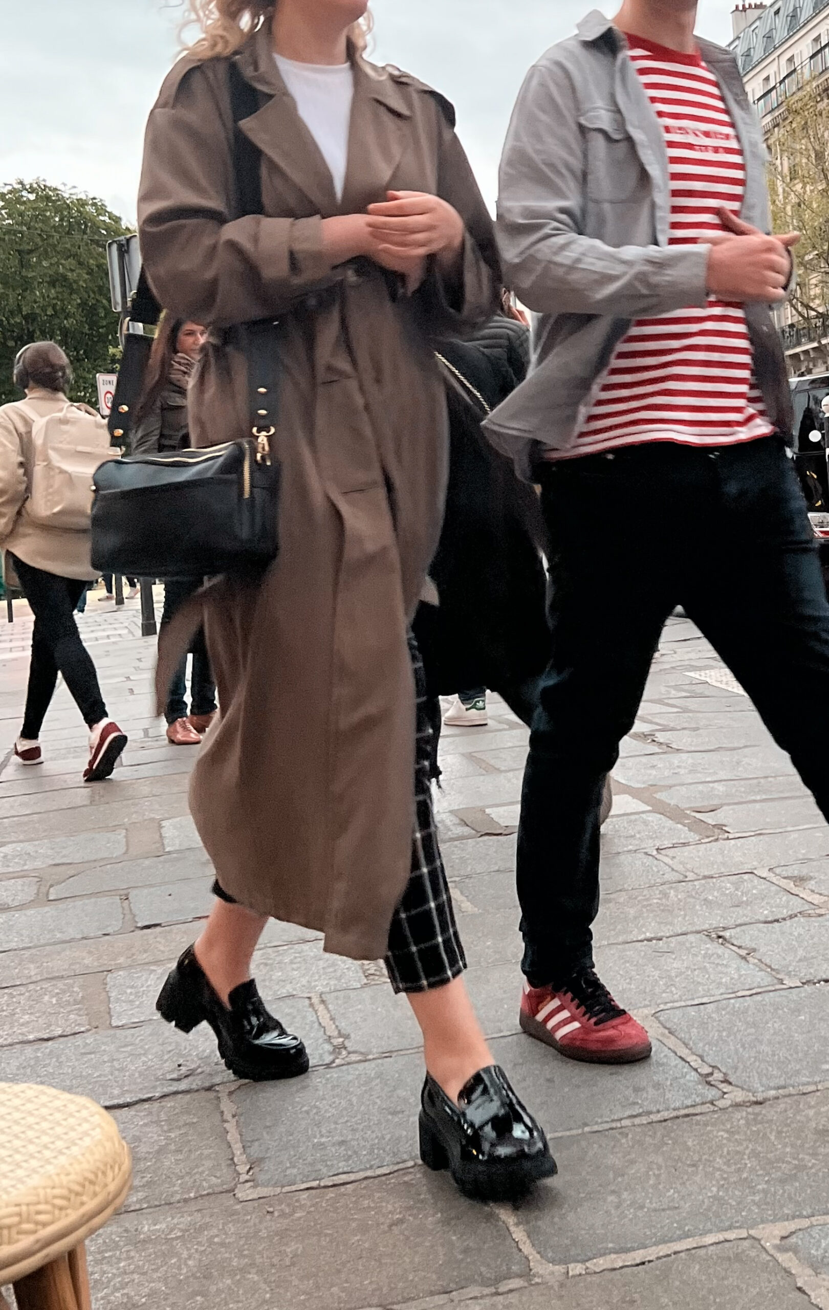 Black patent chunky loafers worn with checked cropped trousers and a trench coat in Paris.