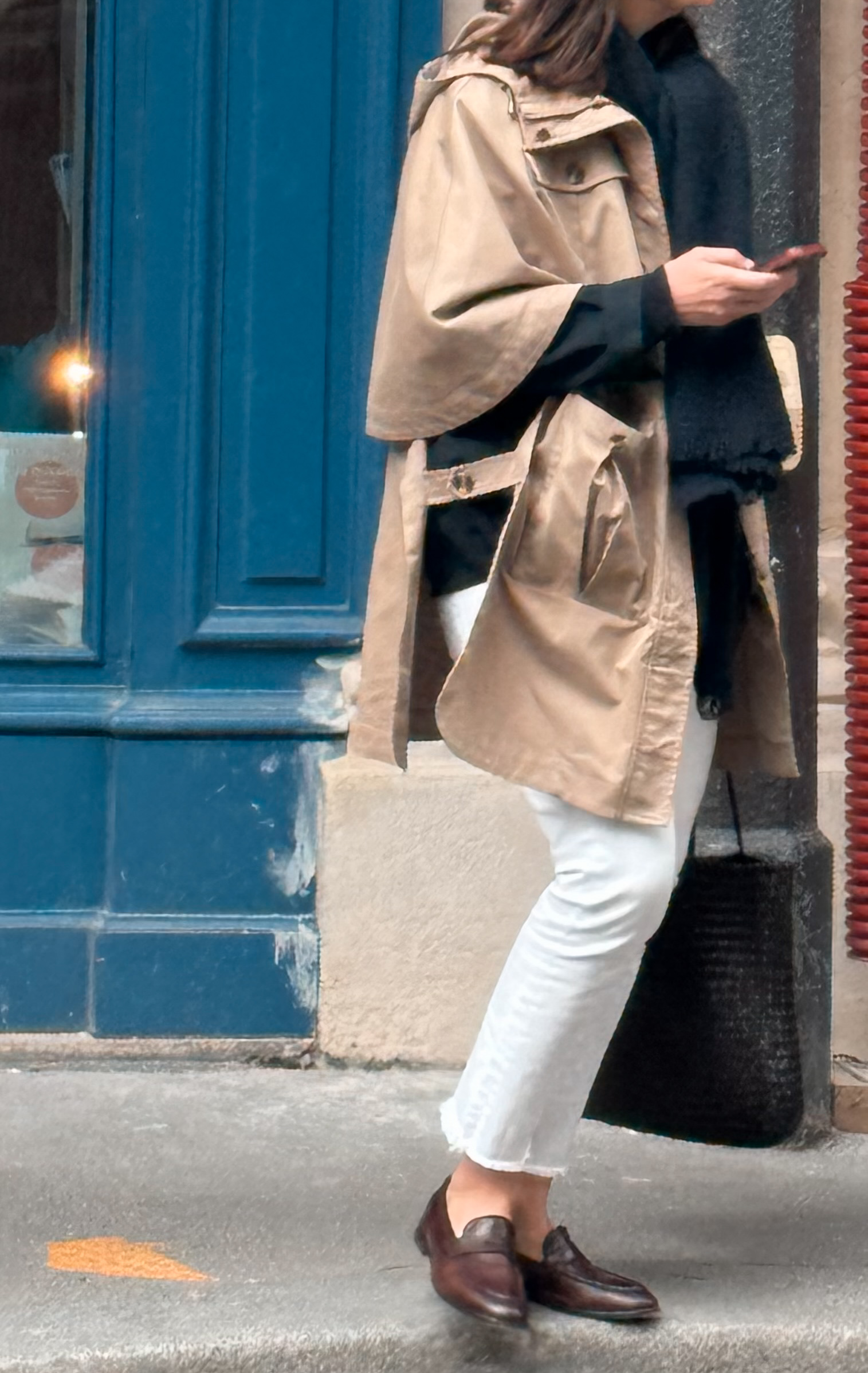 Real Paris street style, a woman in a tan trench and white cropped jeans wearing brown leather loafers.