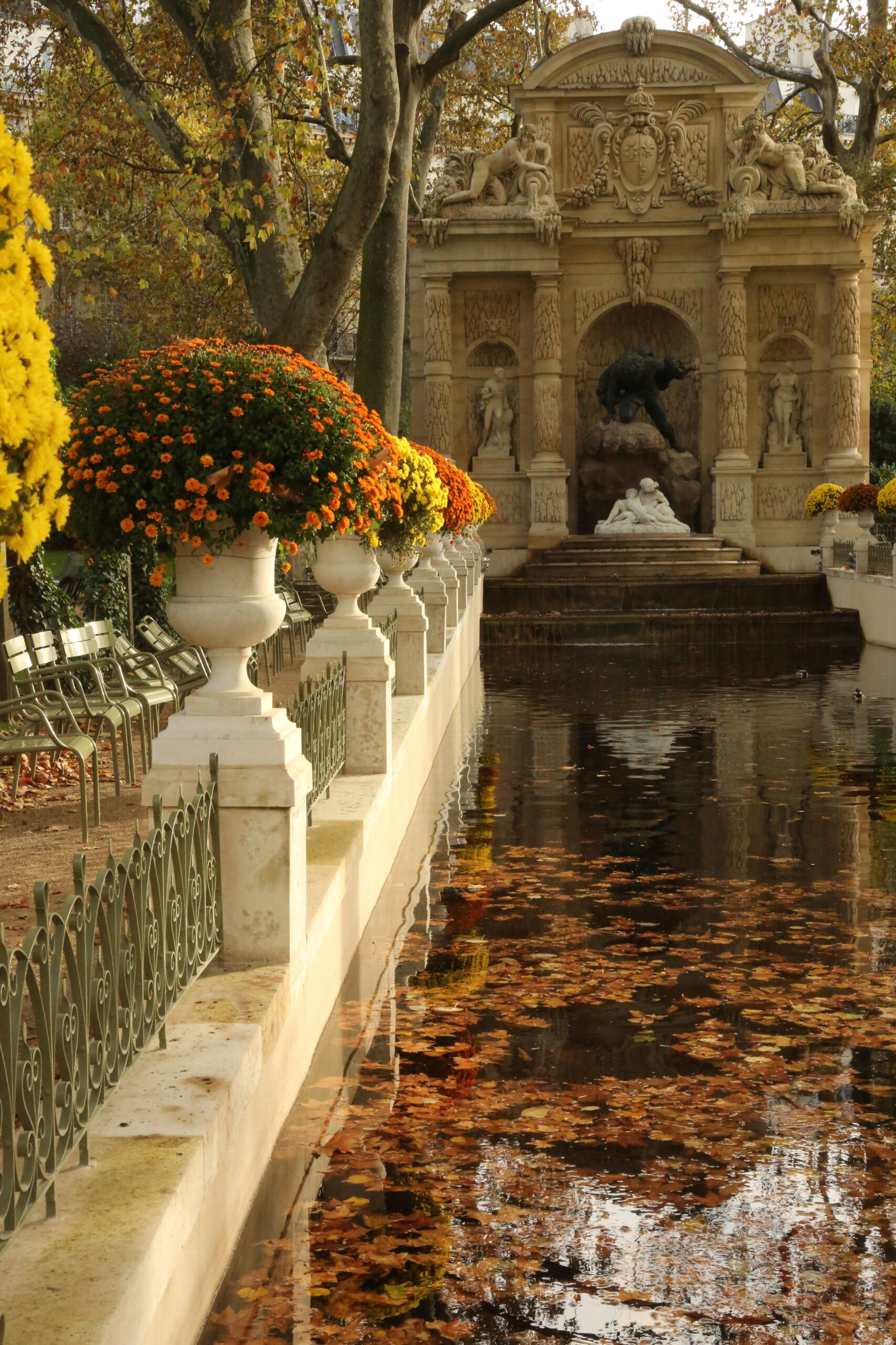 Fountain in Luxembourg Gardens with water and flowers in fall.