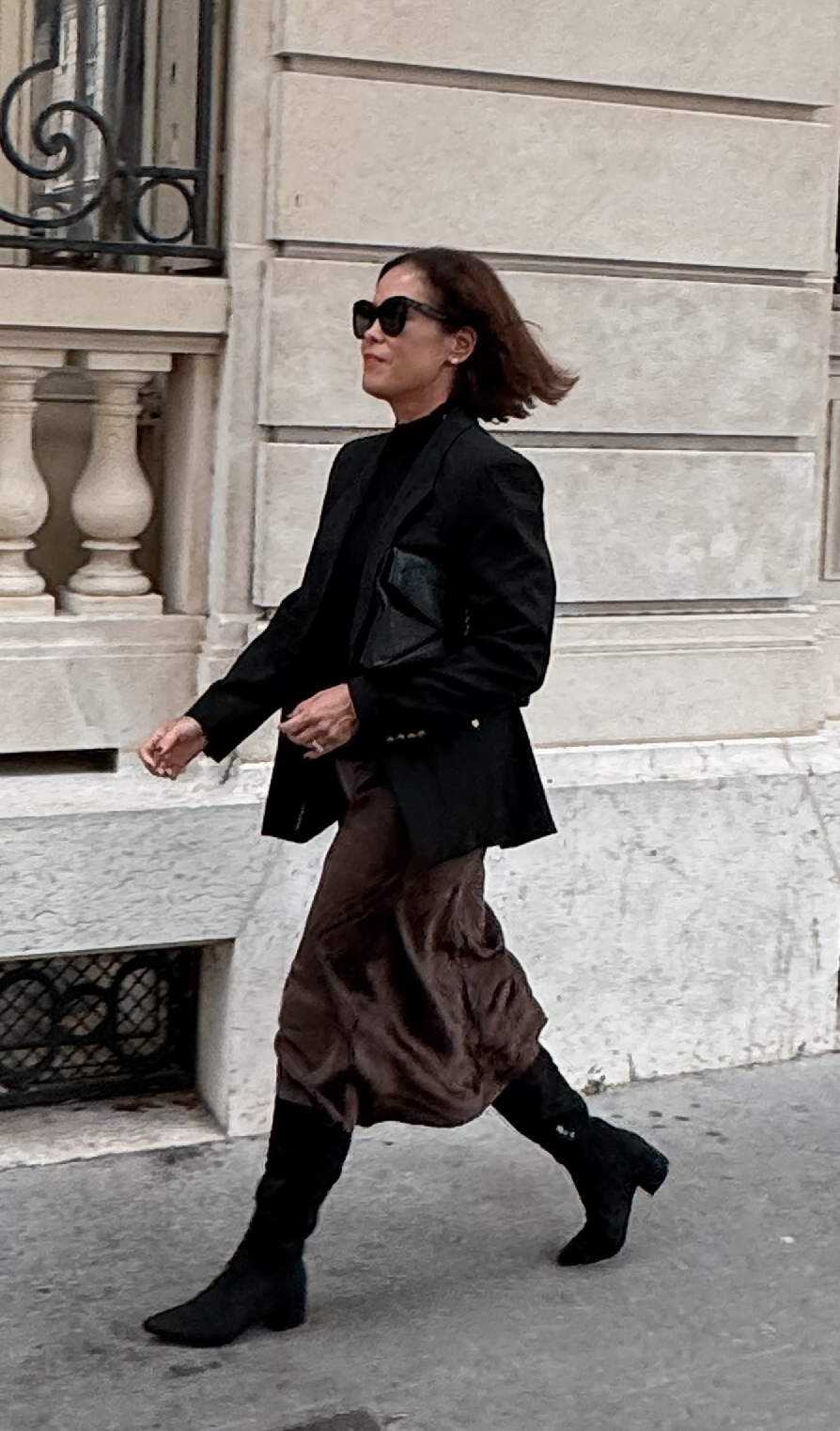 WOMAN WALKING IN SILK SKIRT AND BLACK BLAZER IN PARIS.