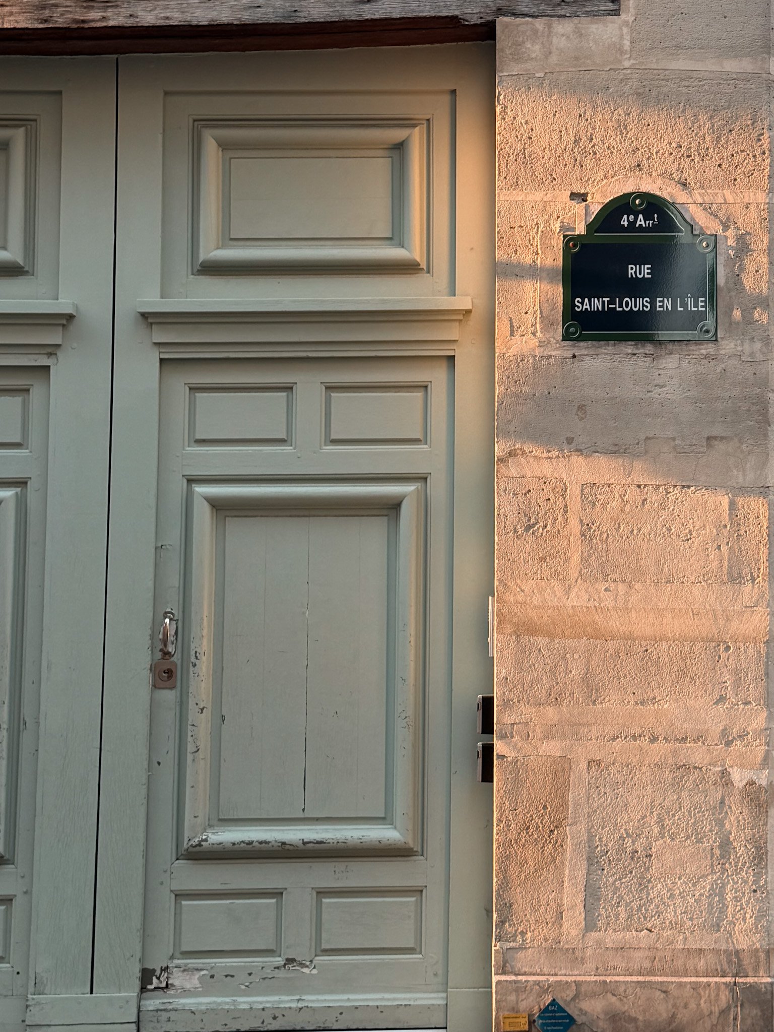 Green door with ile saint louis sign on the wall.