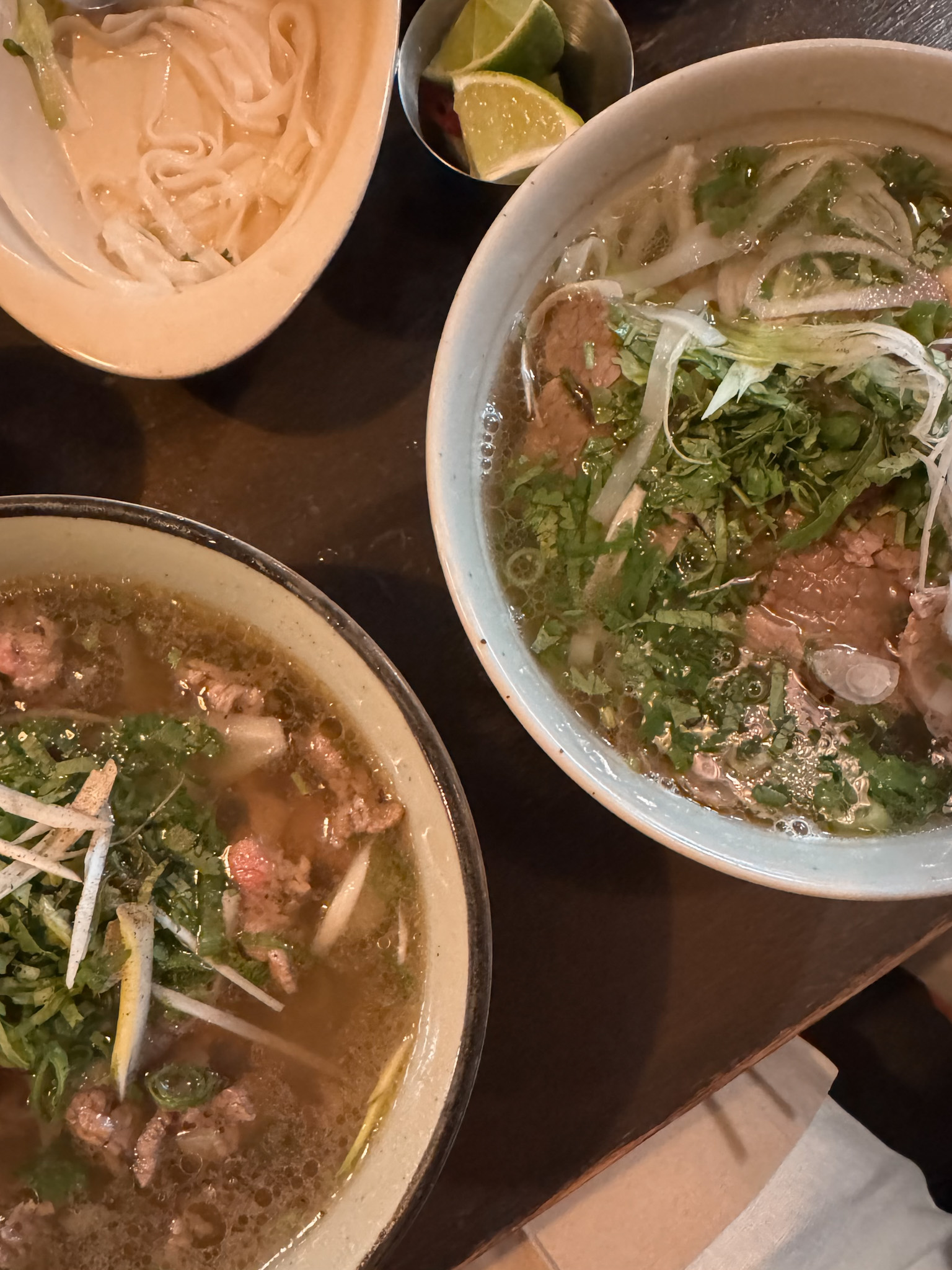 Two bowls of Pho sitting on a table. 