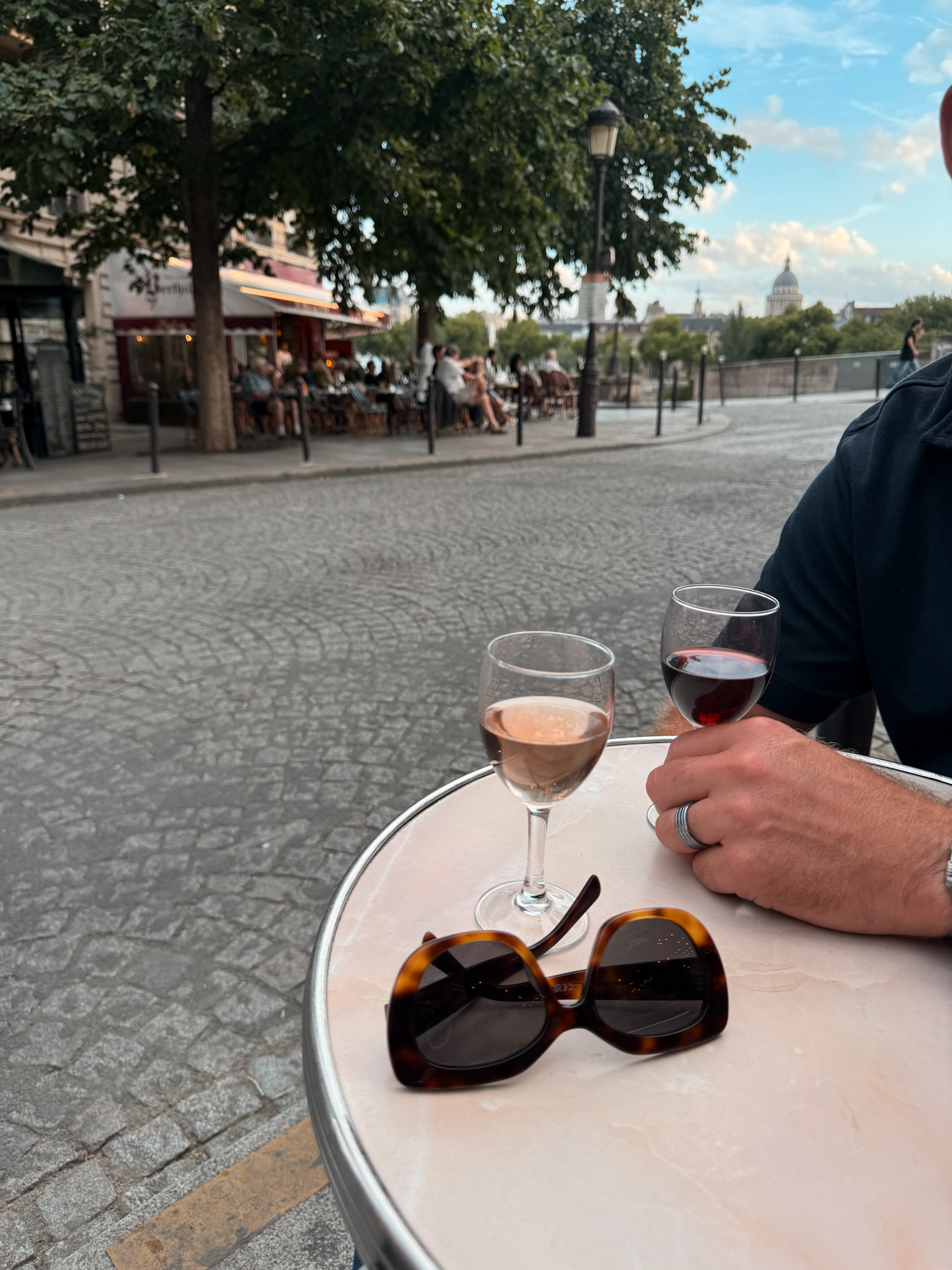 Two wine glasses sitting on a table with sunglasses. 
