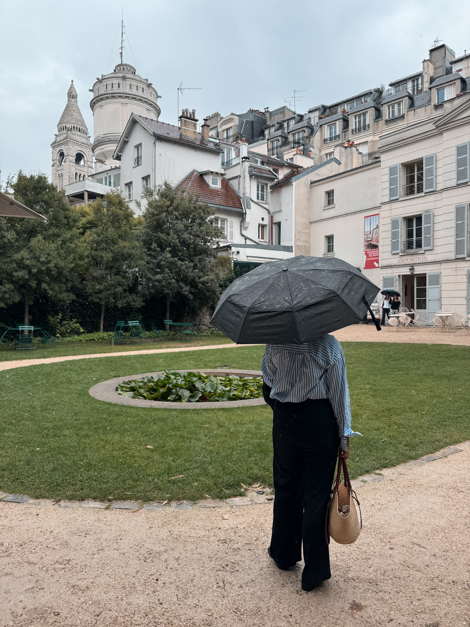 Woman holding umbrella and wearing pants and a stripe shirt.