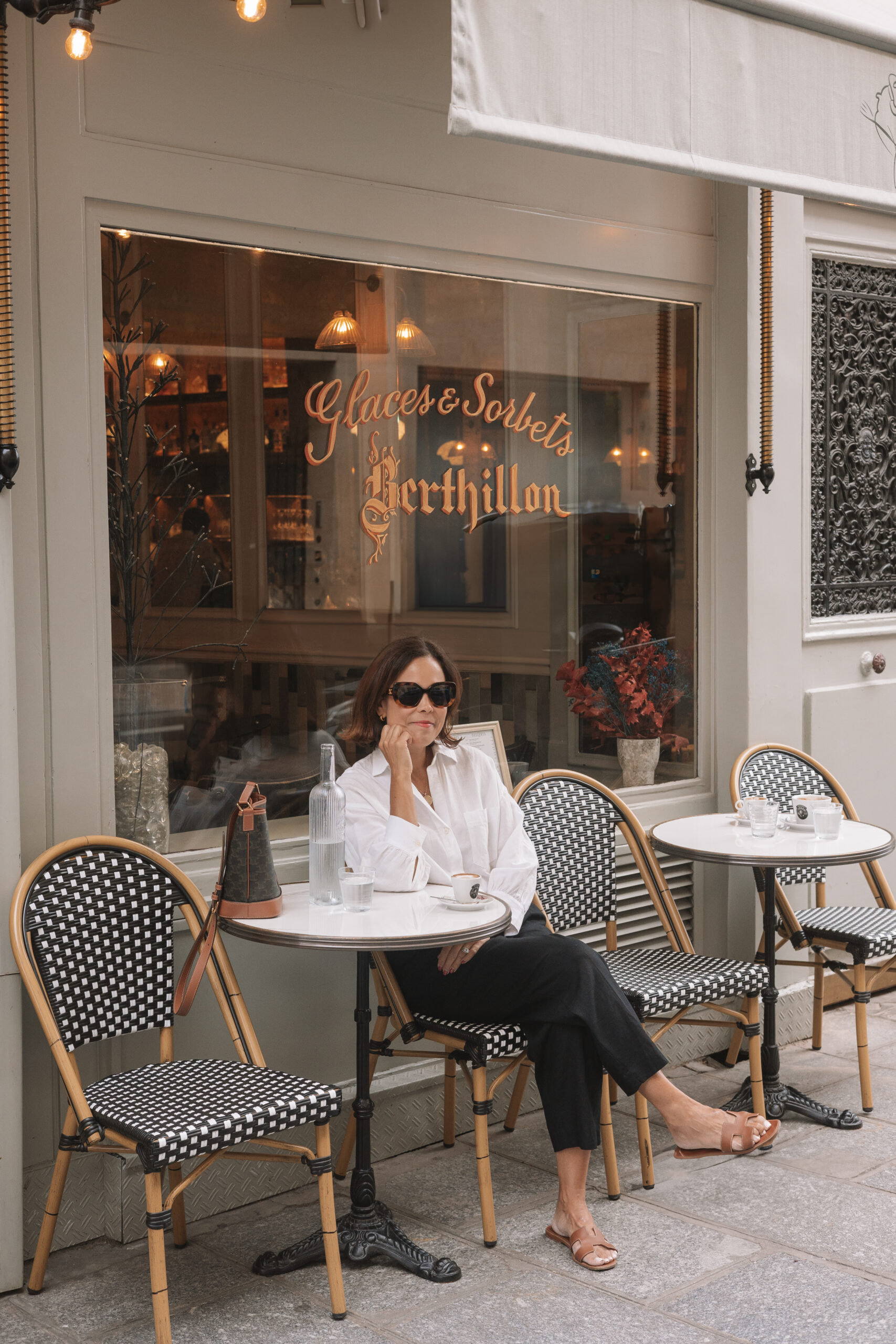 Woman sitting in front of cute cafe in Paris.