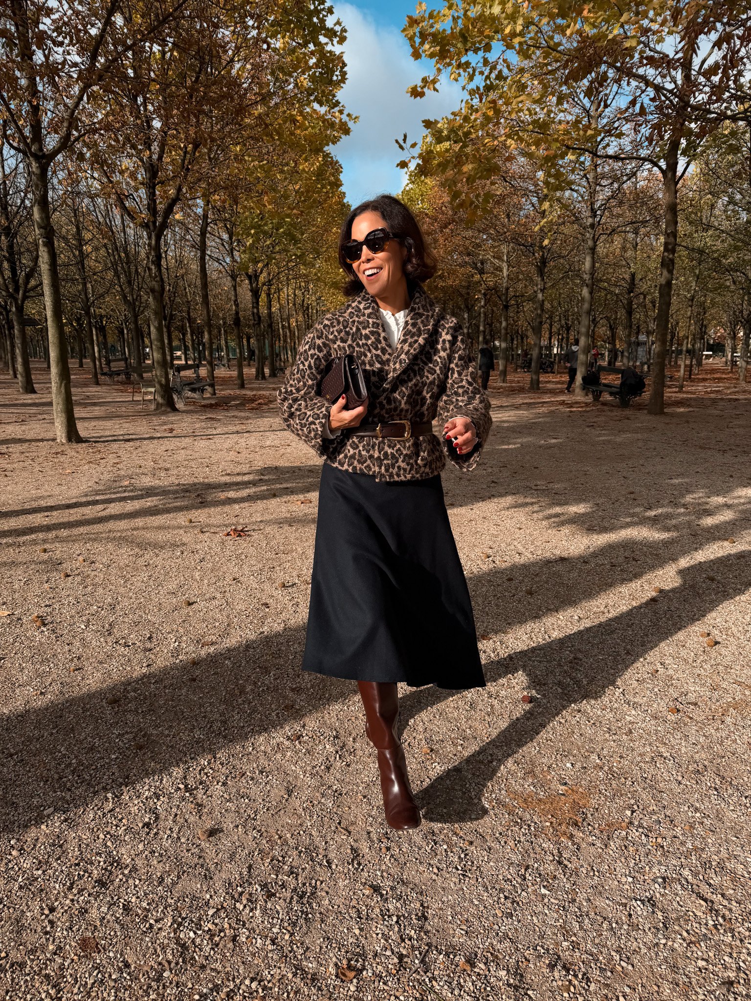 Woman wearing wool skirt with animal print jacket and tall boots.