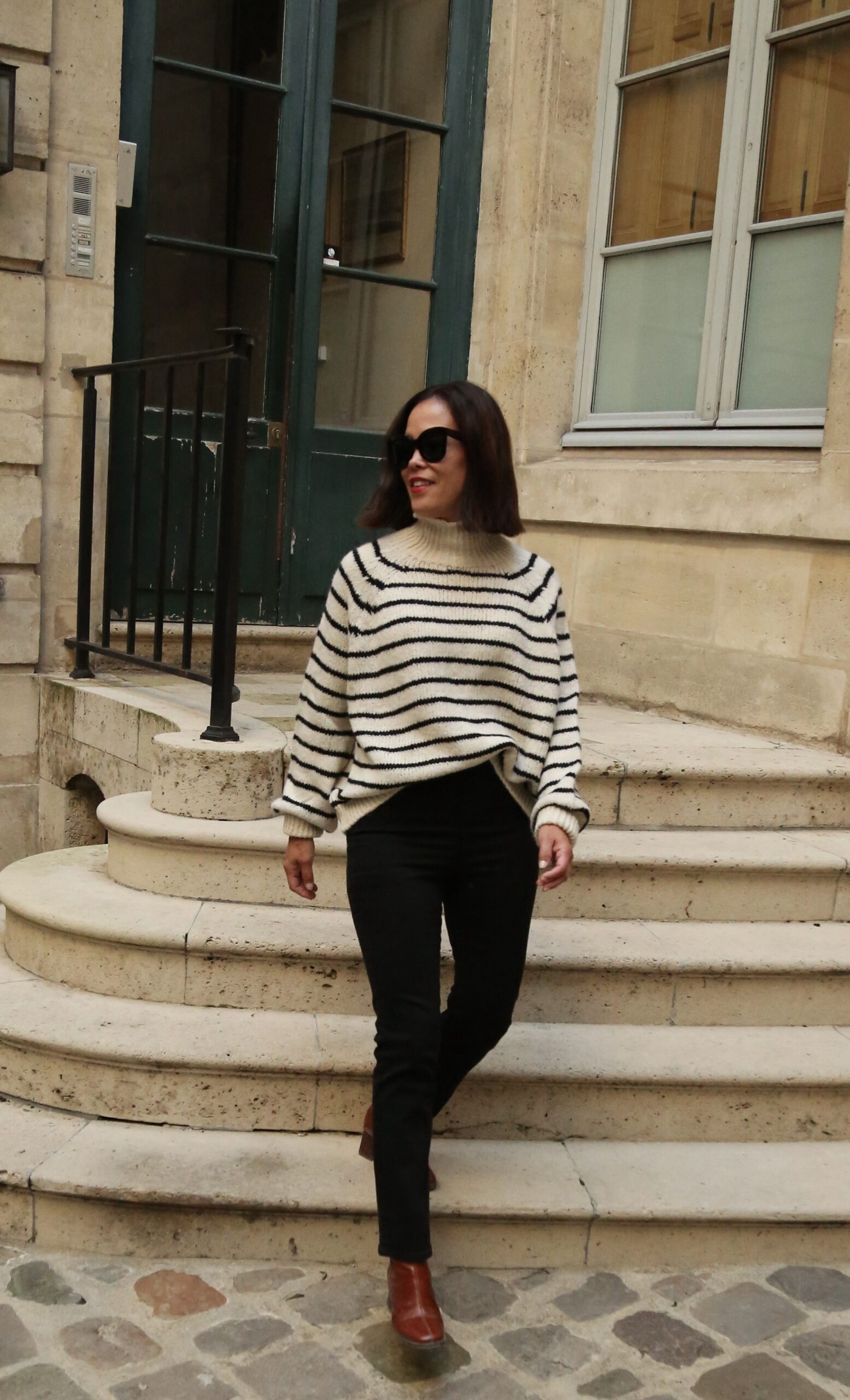 Woman wearing stripe sweater with black denim and boots.