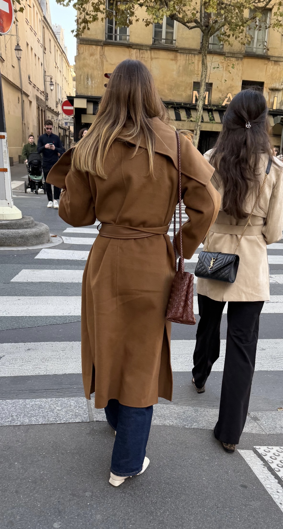Woman walking in Paris wearing brown coat with pants and sneakers in the fall.