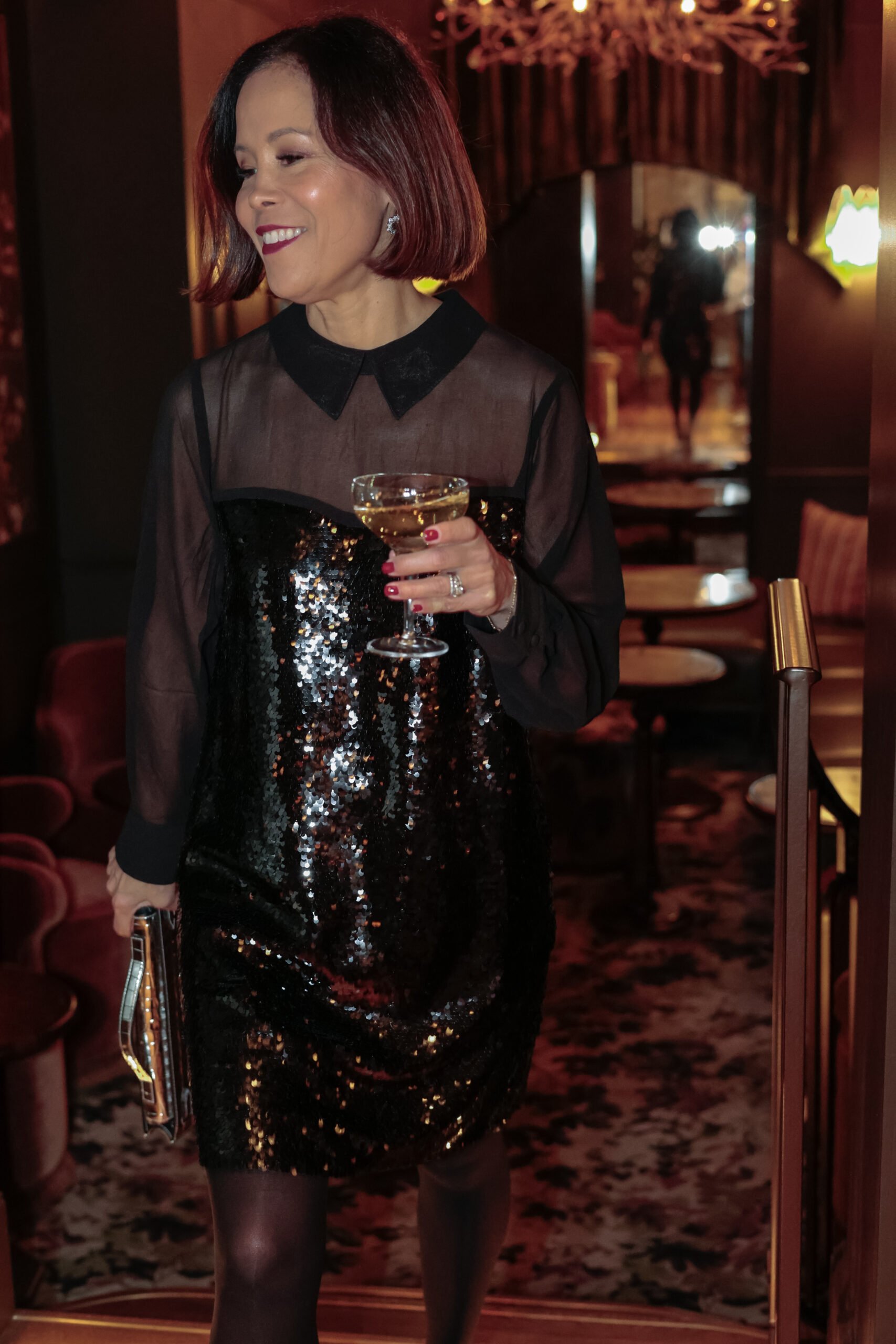 Woman wearing black sequin dress with black tights and slingbacks.