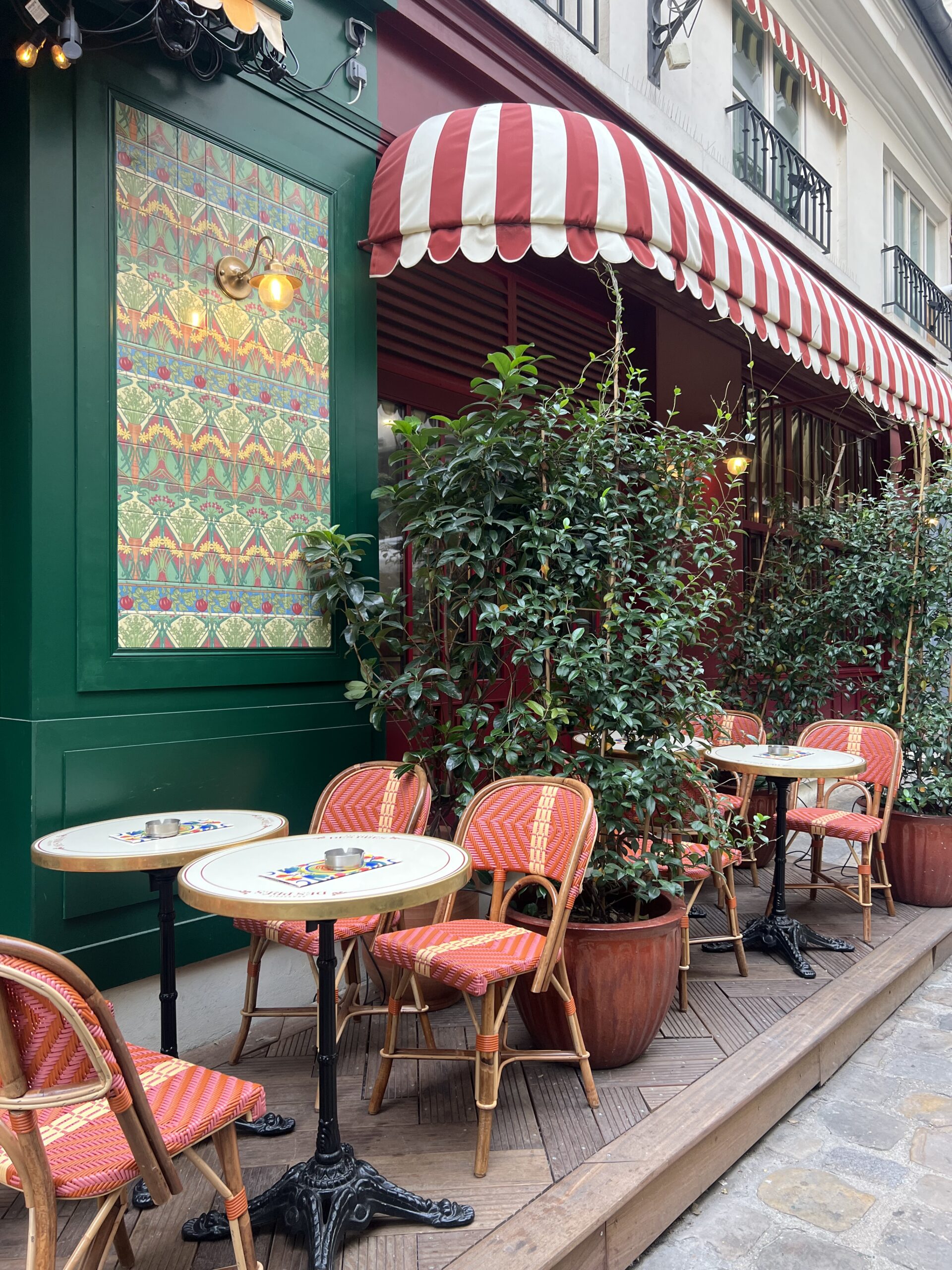 Cafe tables and chairs set up in Paris with red and white awning.