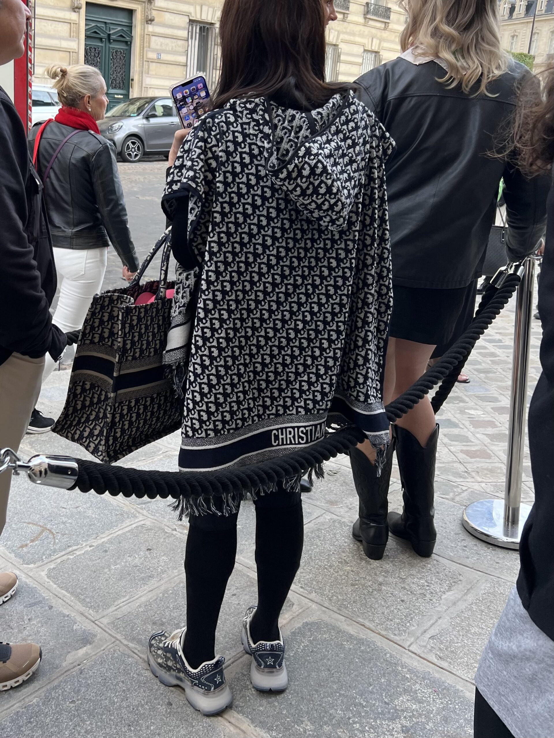 Example of tourist style in Paris featuring logo-heavy layers, athletic sneakers, and oversized bags