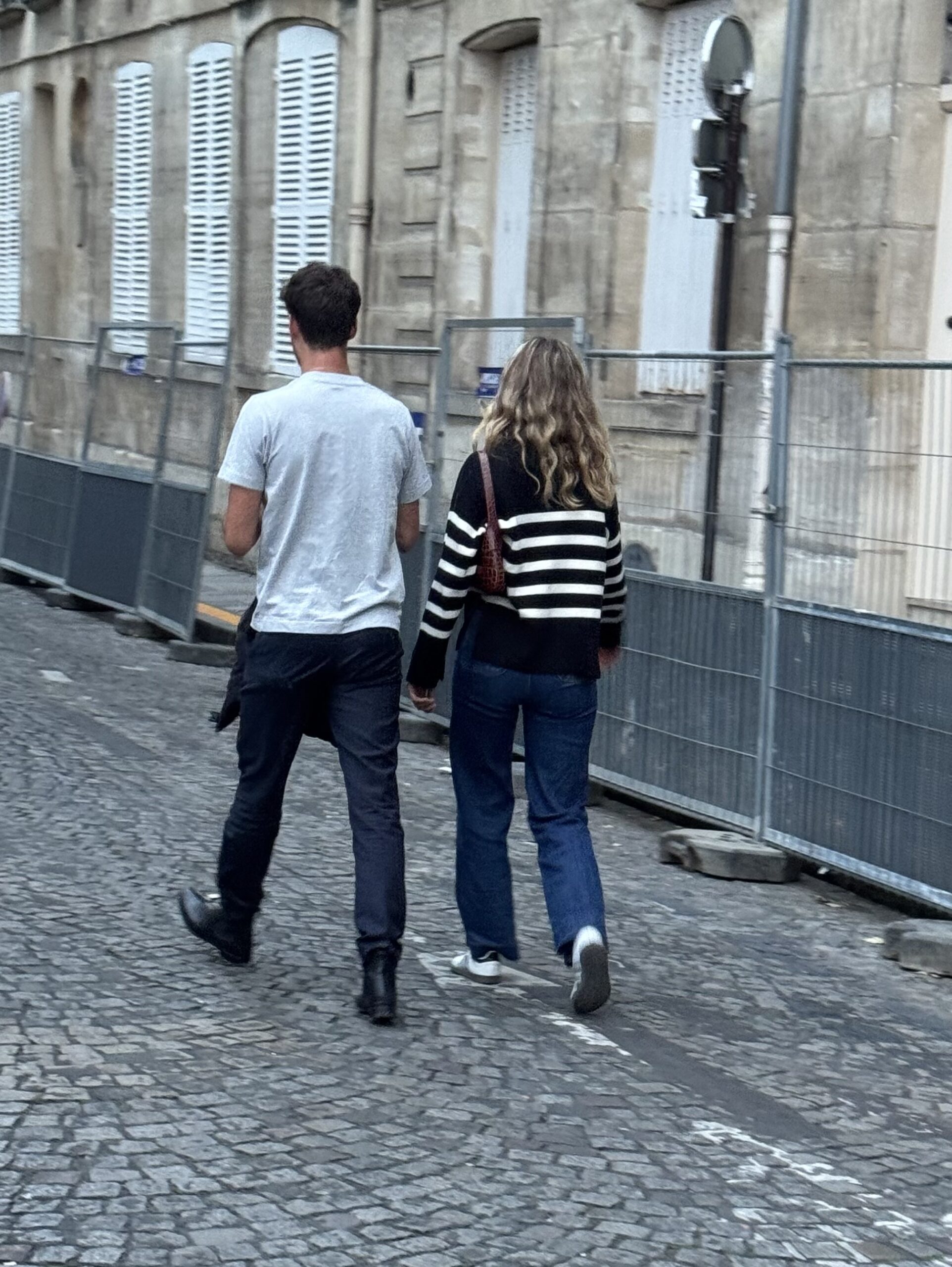 Parisian couple walking through Paris wearing casual, neutral outfits with jeans and classic shoes