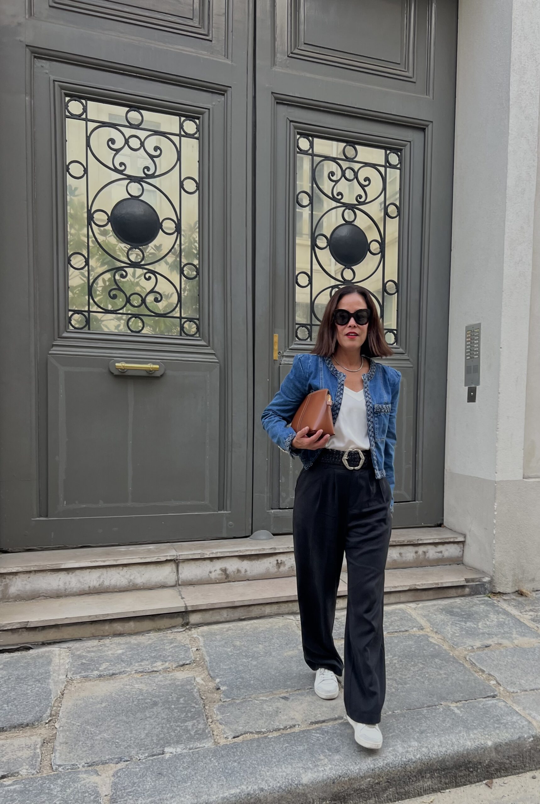 White sneakers for Paris in March paired with black pants and a denim jacket—comfortable walking shoes for cobblestone streets