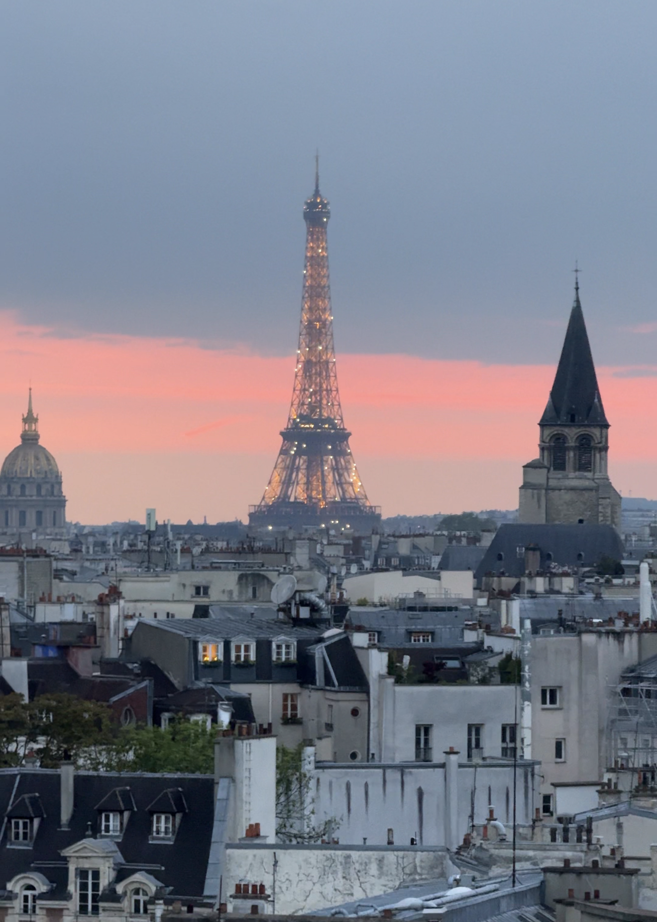 Eiffel tower sparking at sunset on a warm evening when the sky is pink.