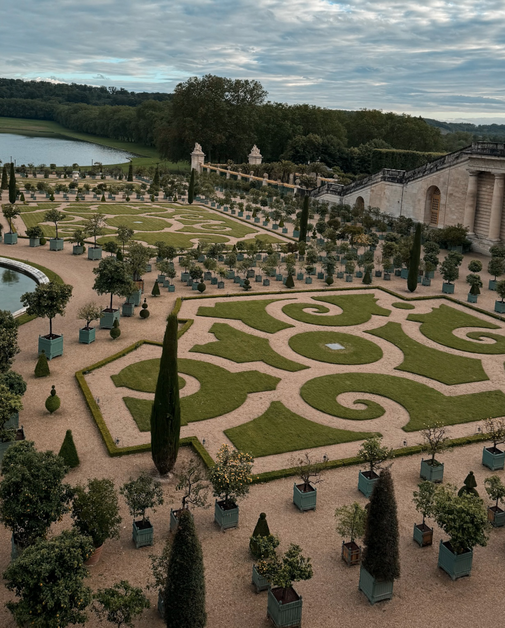 Formal gardens of Versailles with manicured lawns and hedges.