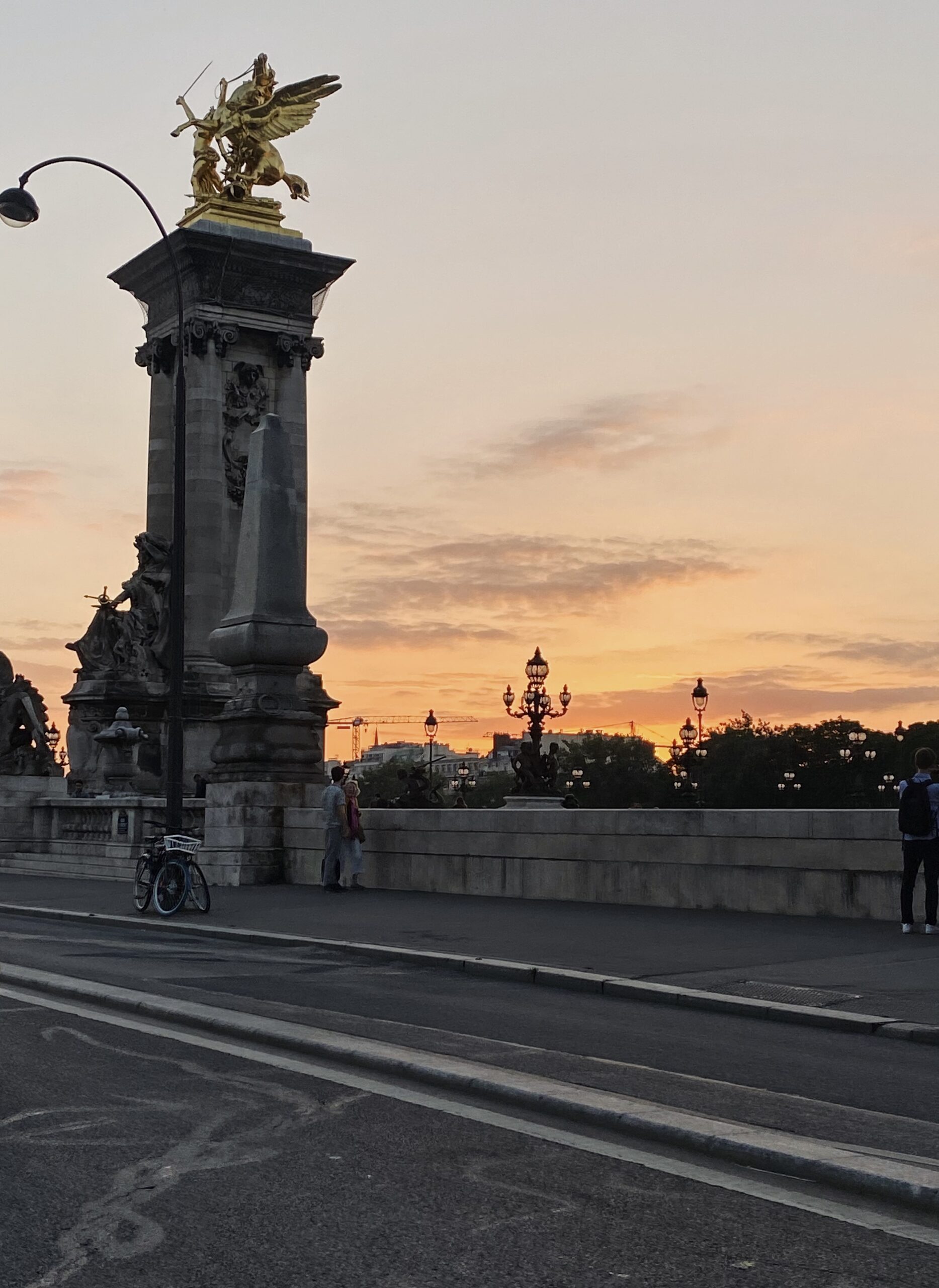 Pont Alexandre III at sunset in Paris with the glowing sky in the background.
