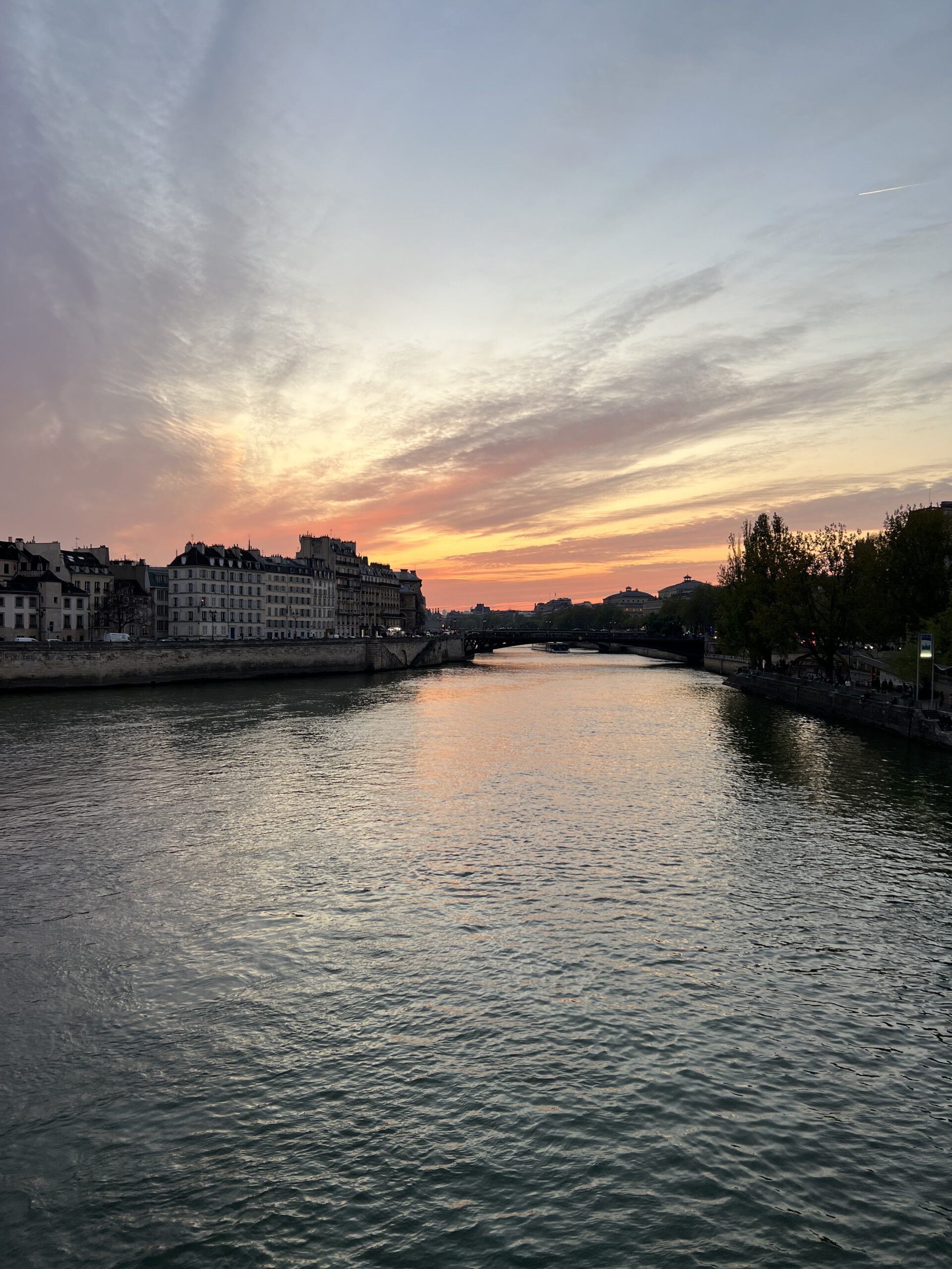 Sunset over the Seine in Paris during the evening sky amongst historic buildings. 