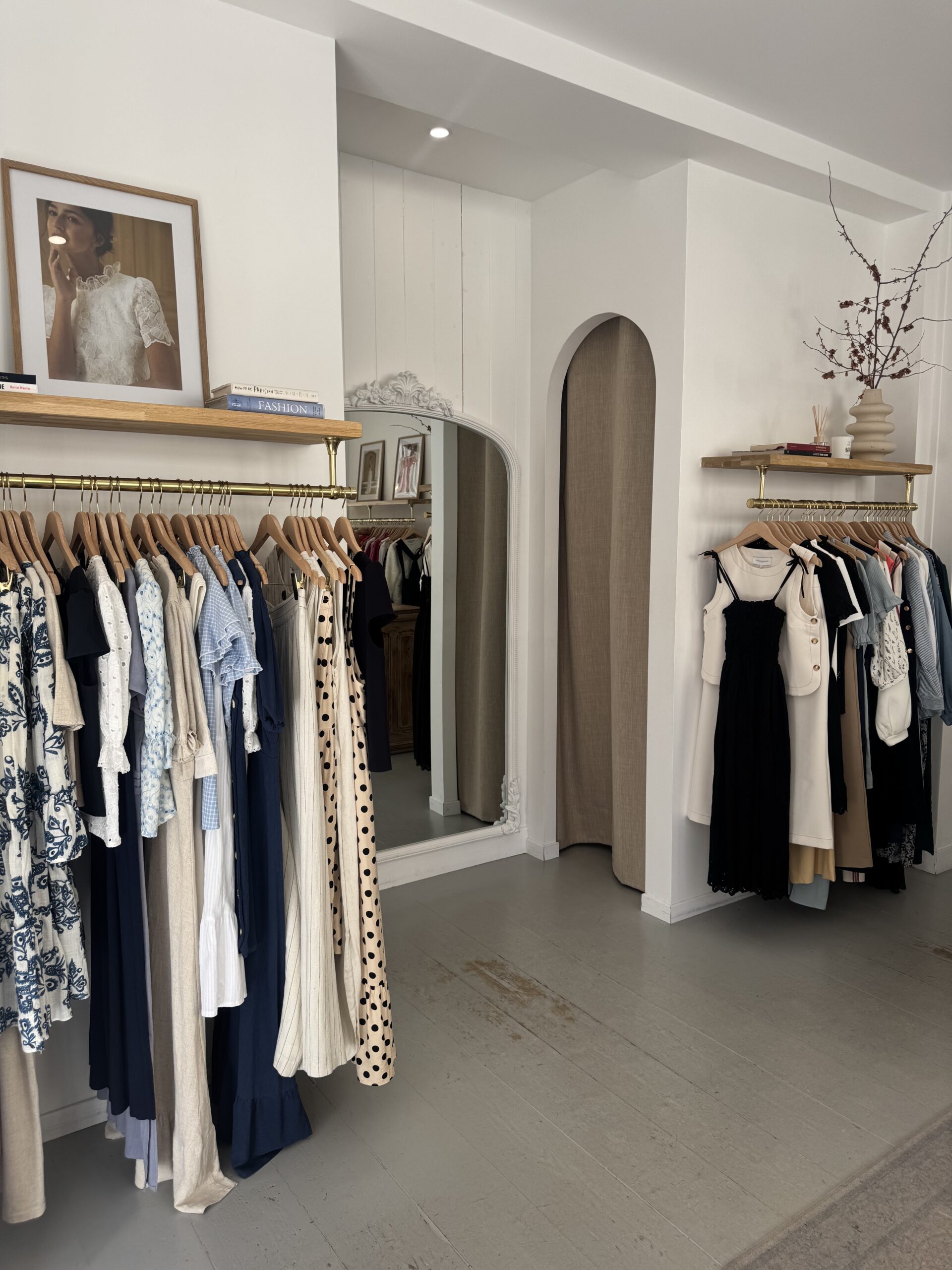 Clothing pieces hung on racks at a clothing store in Paris that is a small boutique style store.