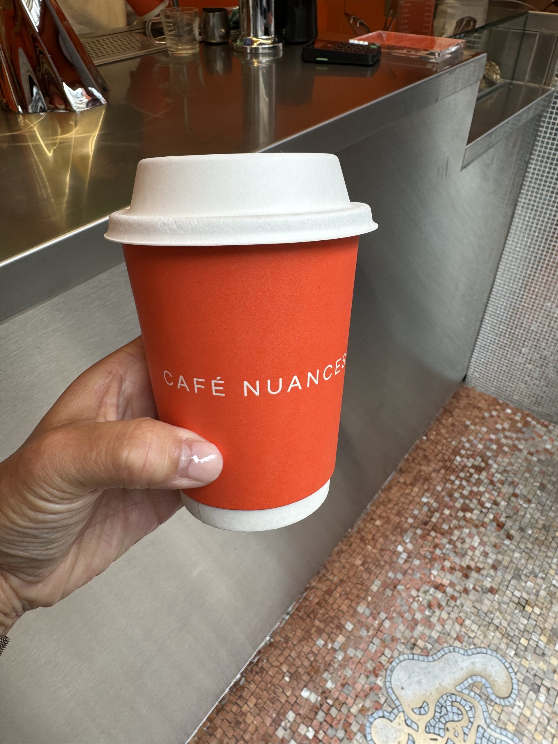 To-go cup of coffee from Café Nuances, a popular craft coffee spot in Saint-Germain, Paris