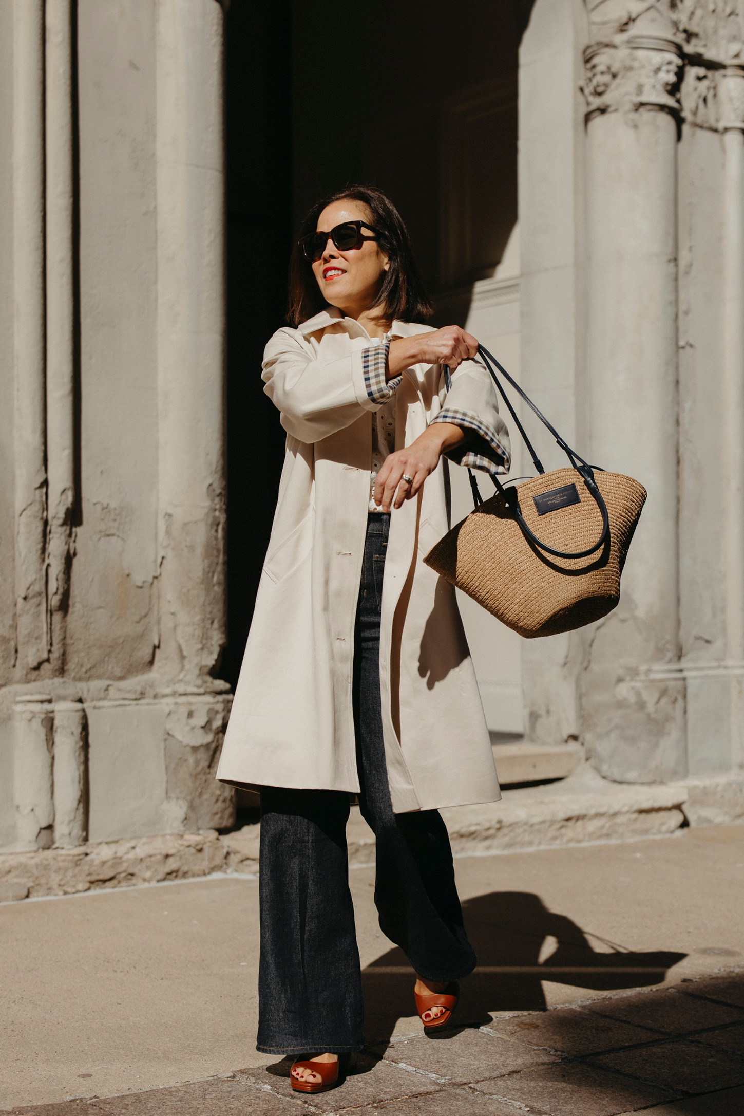 French spring wardrobe outfit with trench coat, straight leg denim, and woven tote bag in Parisian style