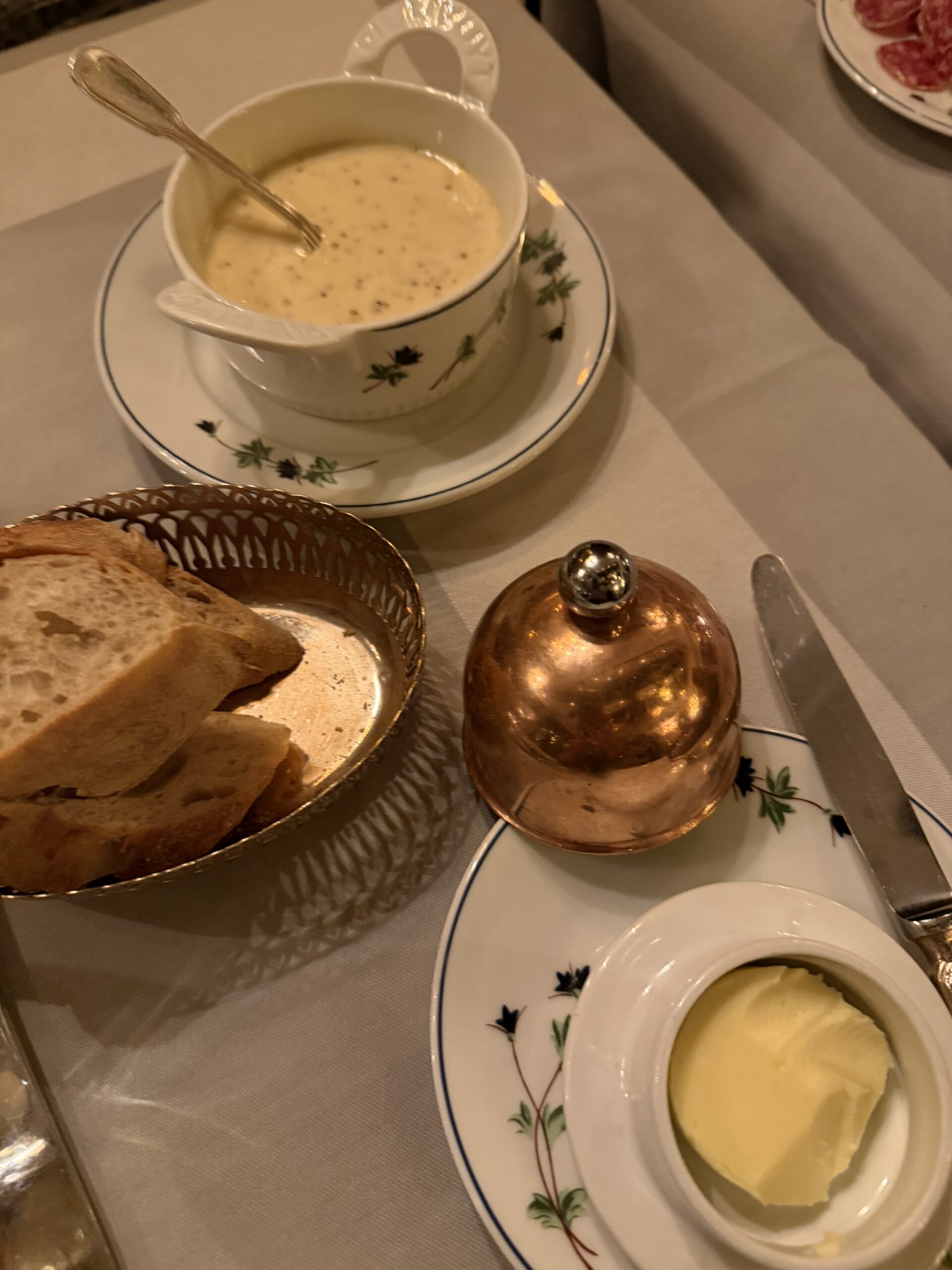 Classic French table setting with soup, bread, and butter at Le Voltaire restaurant in Paris