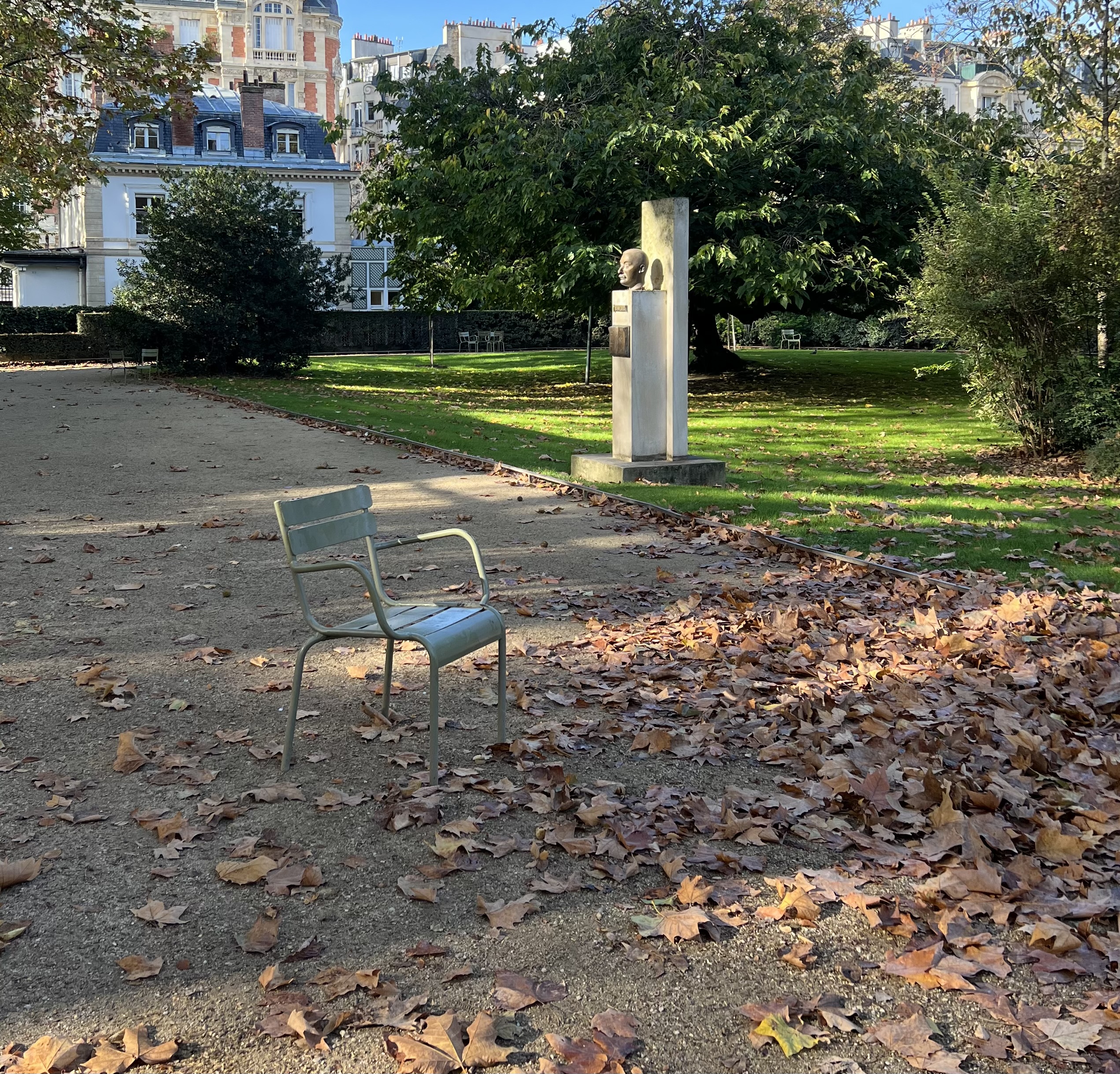 Luxembourg Gardens in Paris during fall with autumn leaves, green chairs, and historic buildings in the background