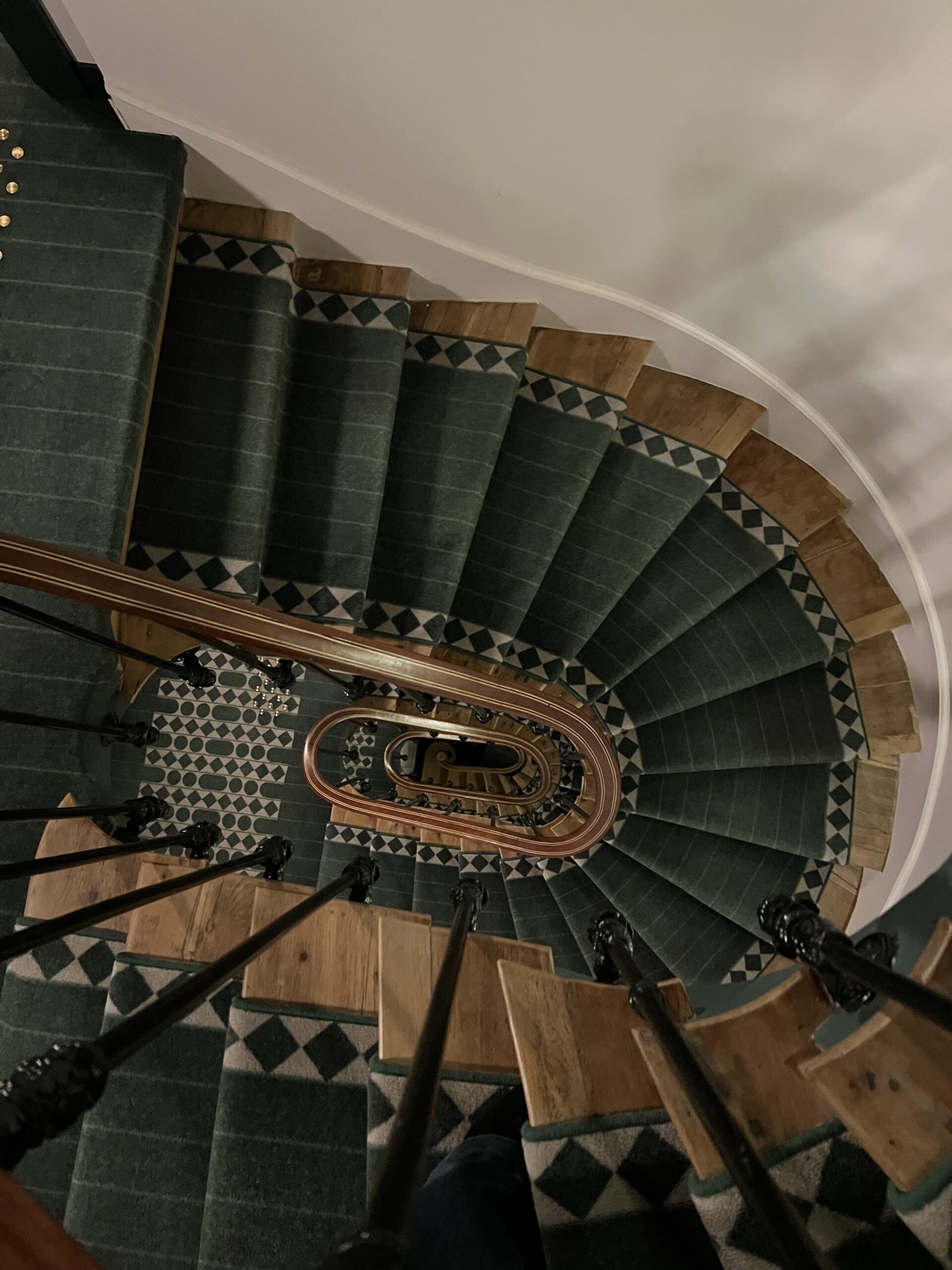Elegant curved staircase with patterned tiles inside a classic Paris hotel