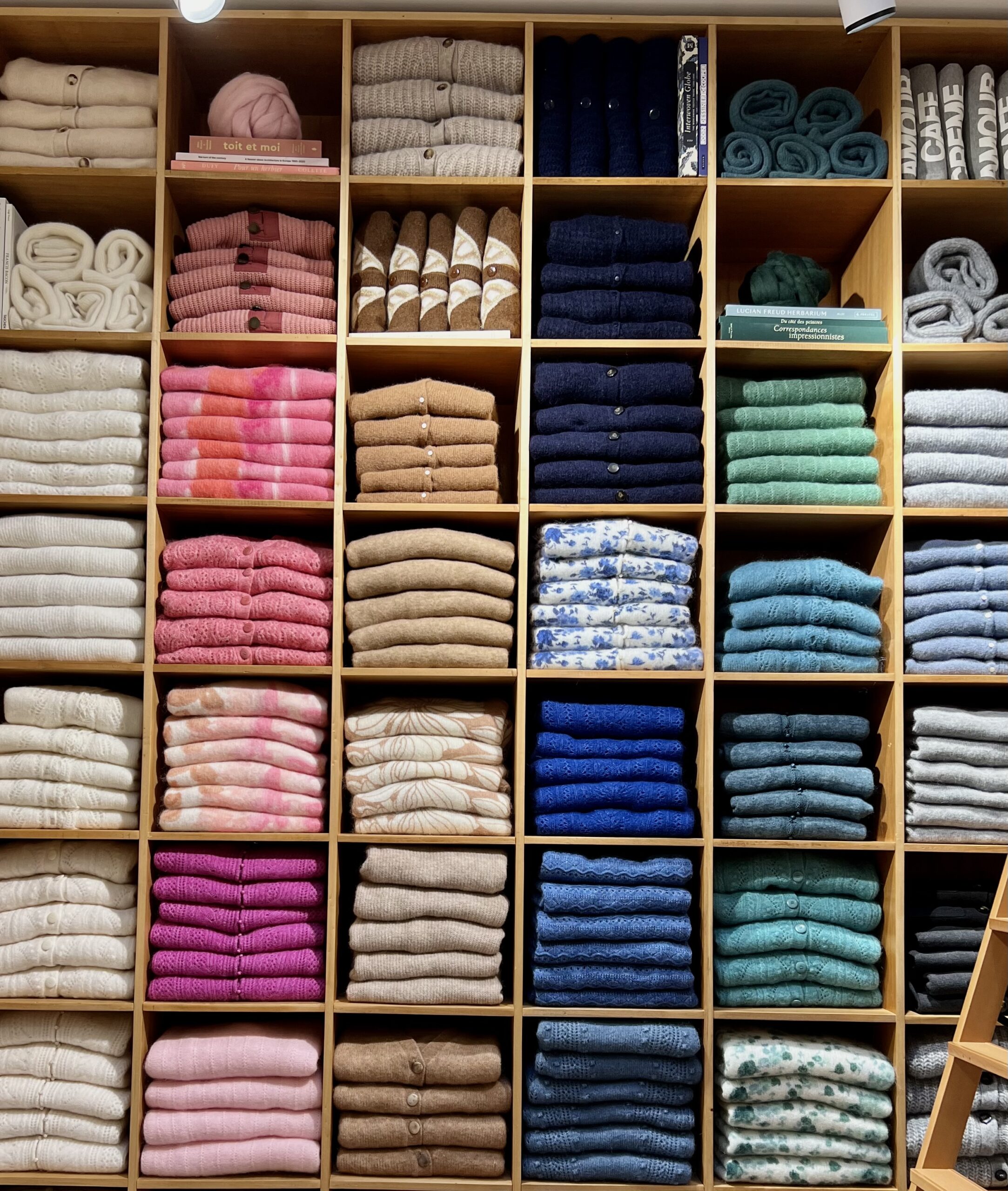 Colorful sweater wall inside a Sézane boutique in Paris showcasing classic French knitwear