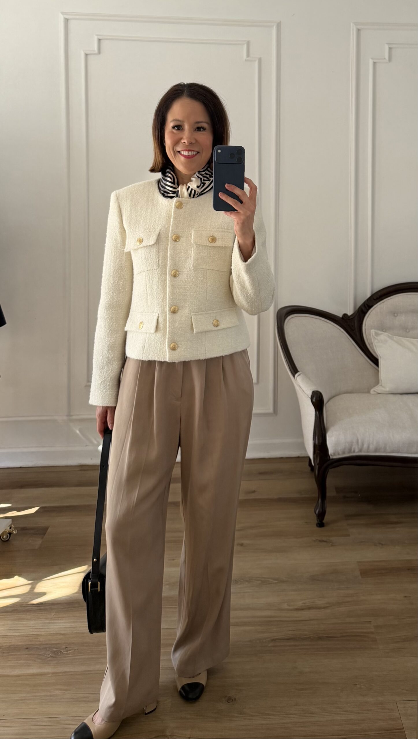 Cream tweed jacket with gold buttons styled with camel wide-leg trousers, a striped silk scarf, and two-tone cap-toe flats — chic spring outfit for women over 40