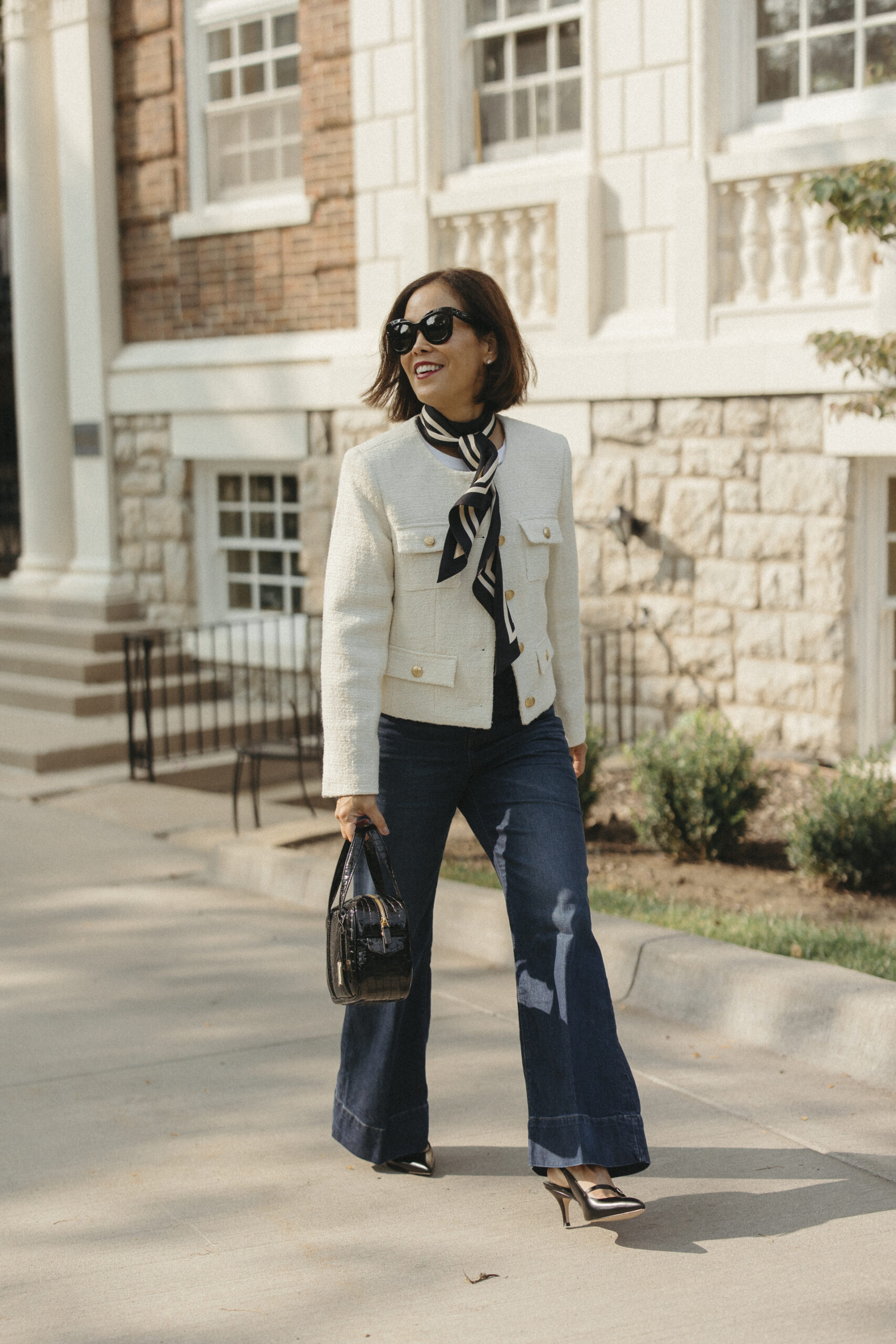 ream tweed jacket styled with dark flare jeans, a black and cream silk scarf, gold slingback heels, black croc bag, and cat-eye sunglasses — chic spring street style