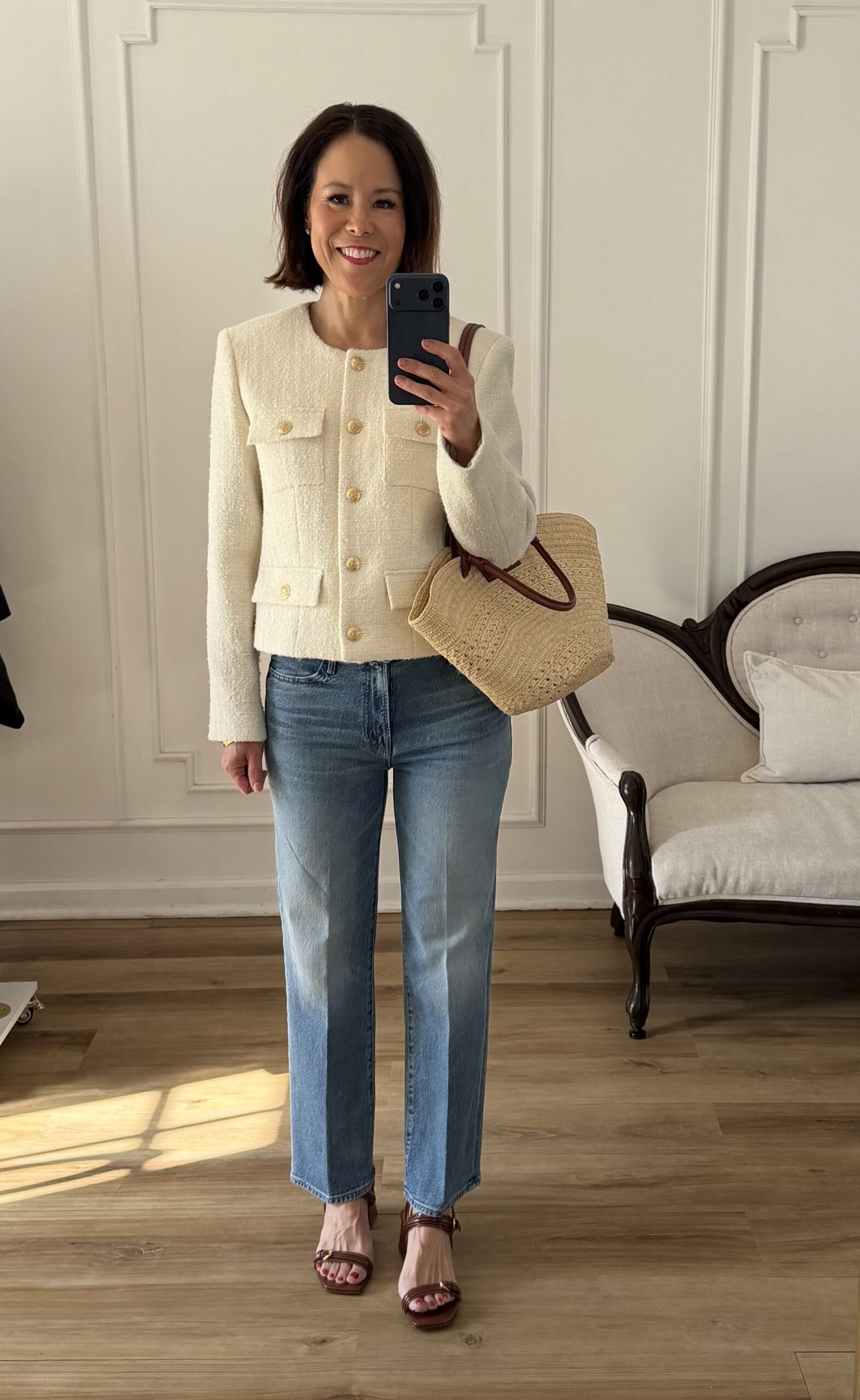 Cream tweed jacket styled with straight leg jeans, cognac heeled sandals, and a woven straw tote bag — a chic spring outfit idea