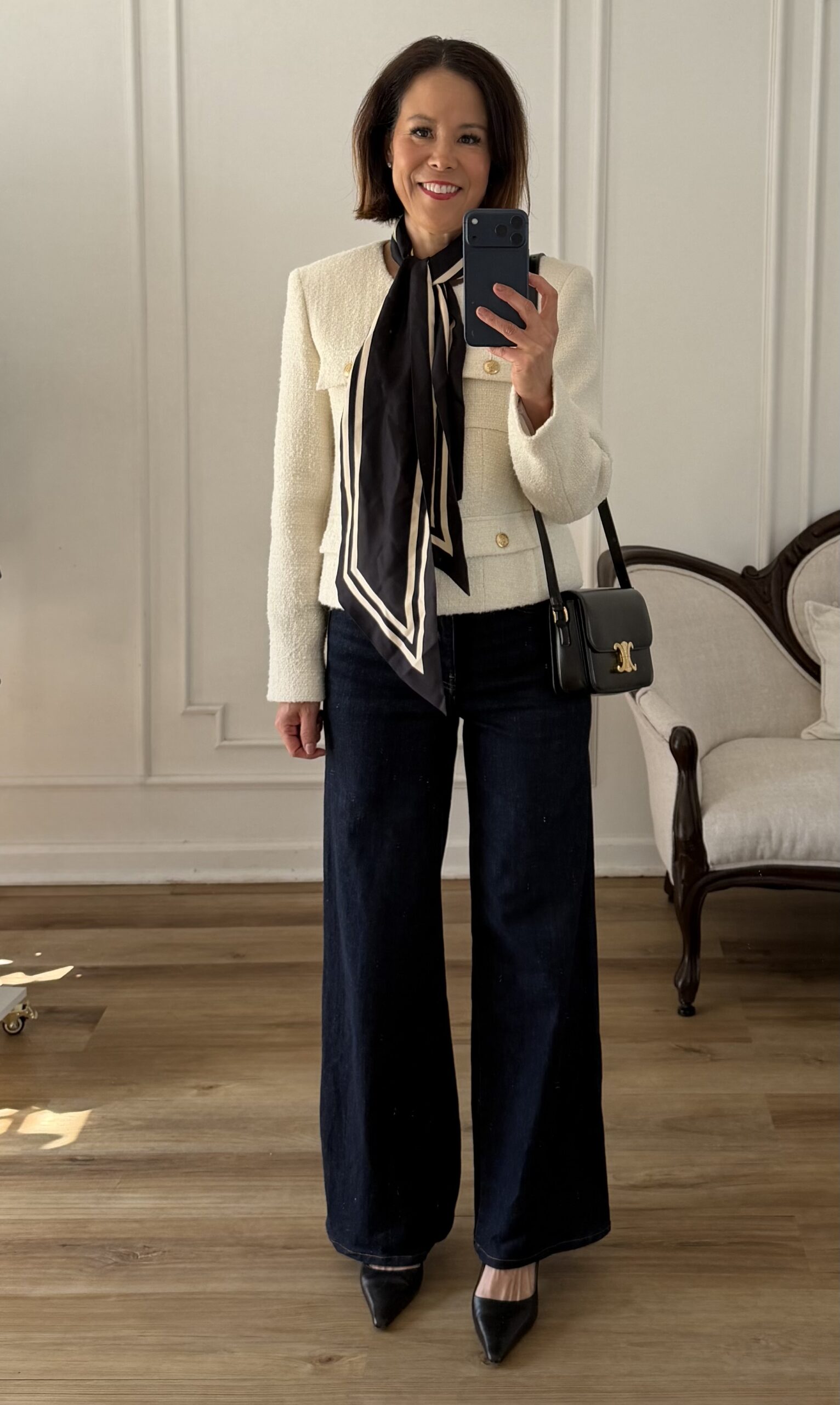 Cream tweed jacket outfit with dark wide leg jeans, a black and cream silk neck scarf, black pointed toe heels, and a structured black crossbody bag

