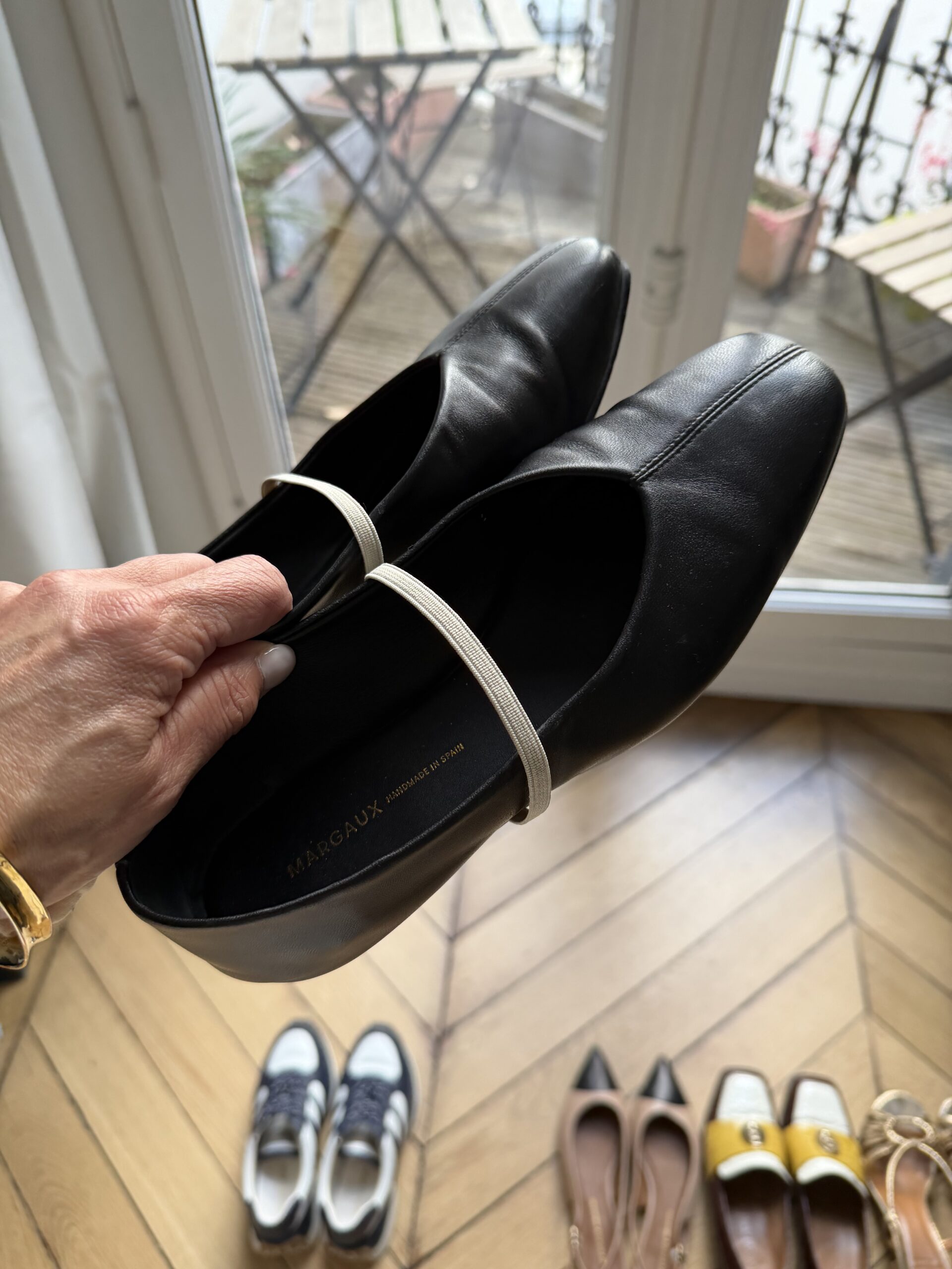Black Margaux ballet flats handmade in Spain held up in Paris apartment with herringbone wood floors — best ballet flats French capsule wardrobe