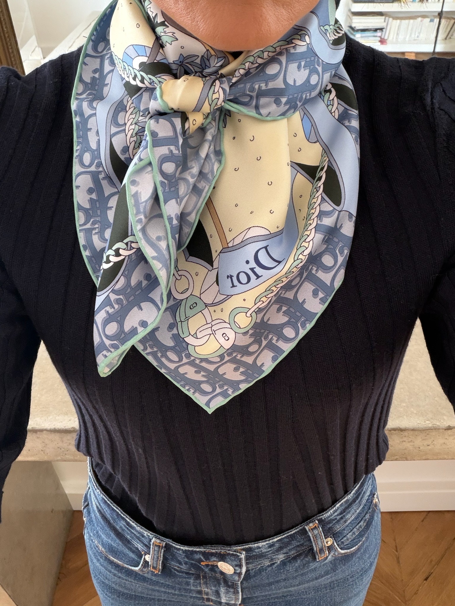 Close-up of silk scarf tied at neck over black ribbed knit top — how to wear a scarf French capsule wardrobe style