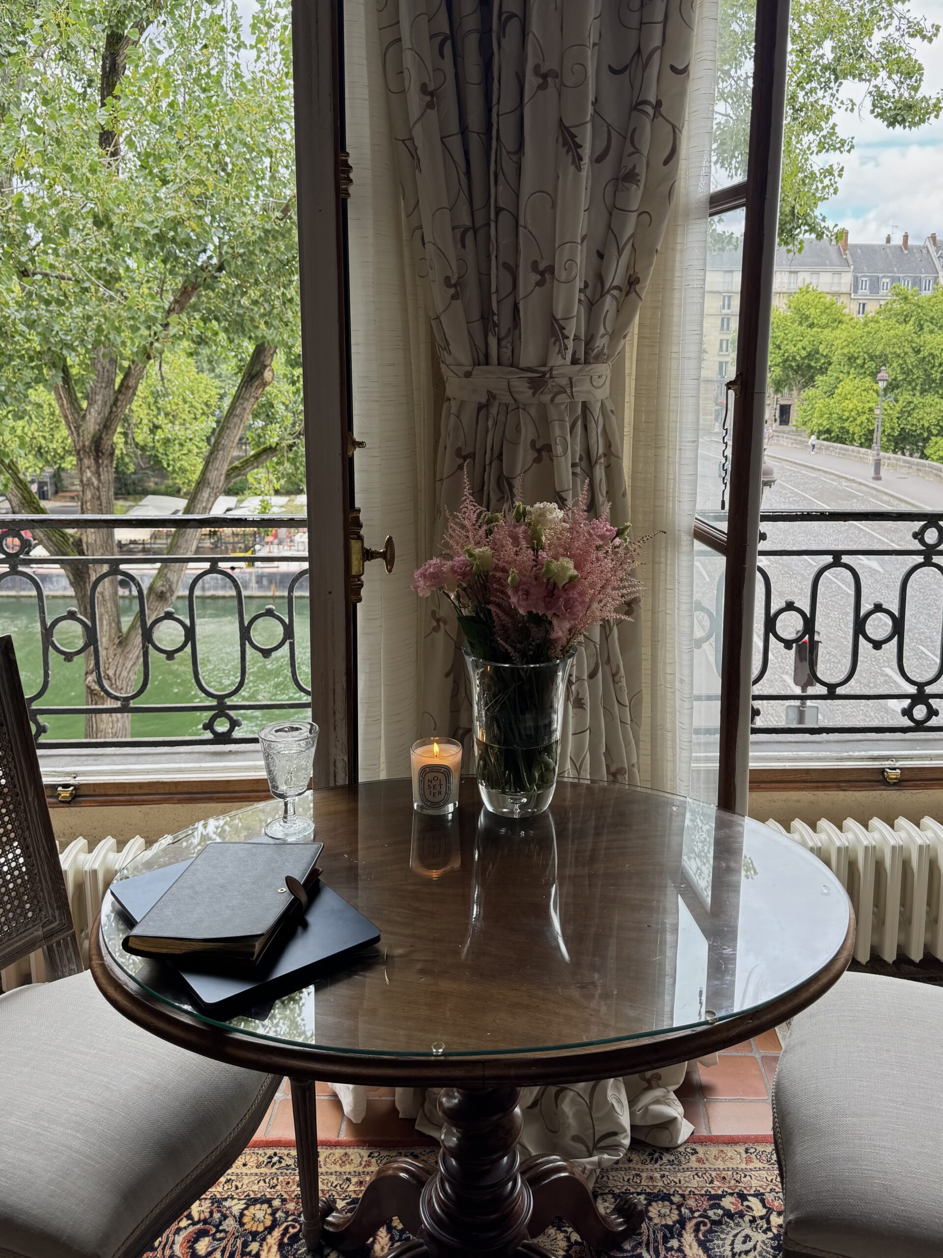 Paris apartment rental with a view of the Seine in summer — flowers, candle, and French doors open to the river